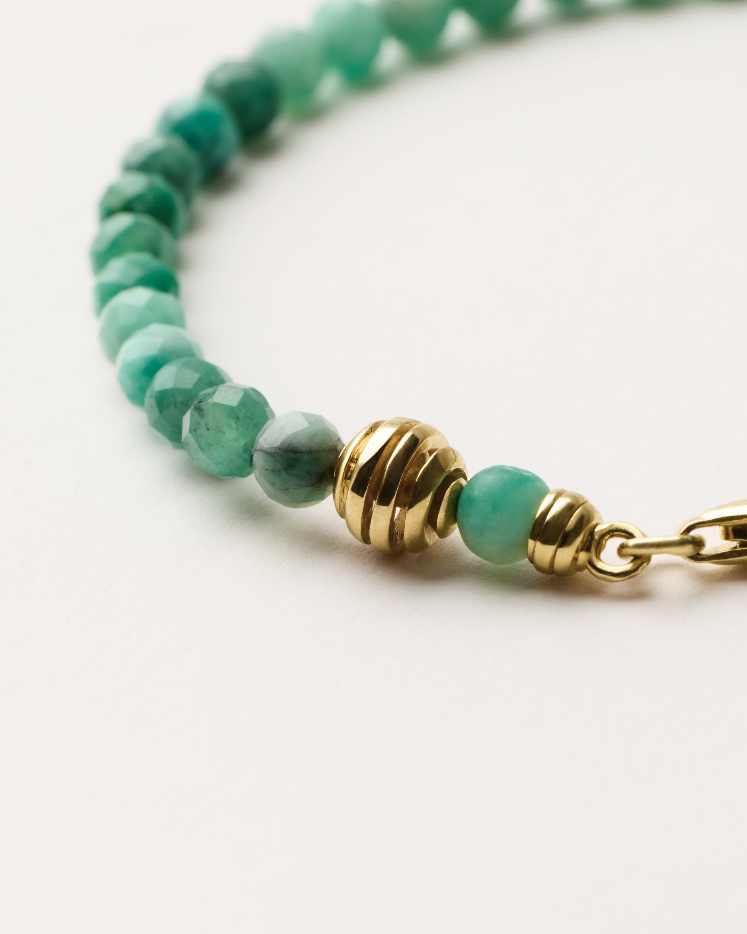 ETERNA VIRID Emerald bracelet with polished gold spiral bead, 4 cm extension chain and clasp, arrowhead-shaped fantasy signature, and 4 mm faceted emerald bead strand.