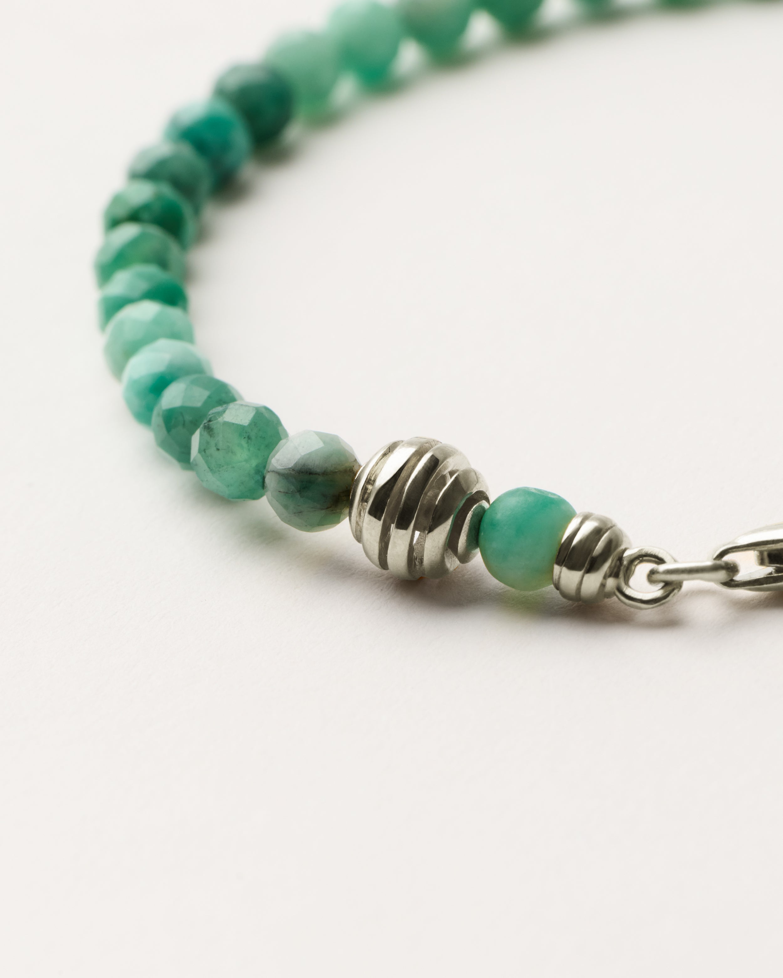 ETERNA VIRID Emerald bracelet with polished silver spiral bead, 4 cm extension chain and clasp, arrowhead-shaped fantasy signature, and 4 mm faceted emerald bead strand.
