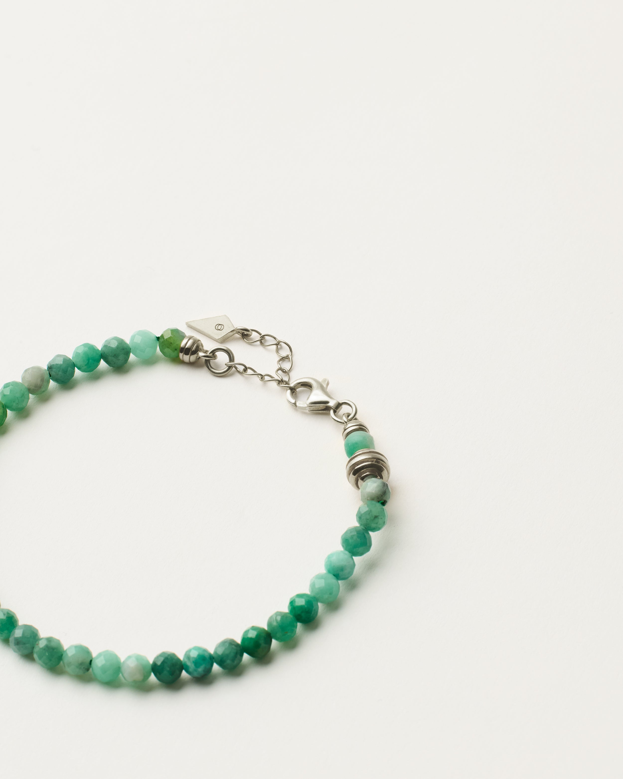 ETERNA VIRID Emerald bracelet with polished silver spiral bead, 4 cm extension chain and clasp, arrowhead-shaped fantasy signature, and 4 mm faceted emerald bead strand.
