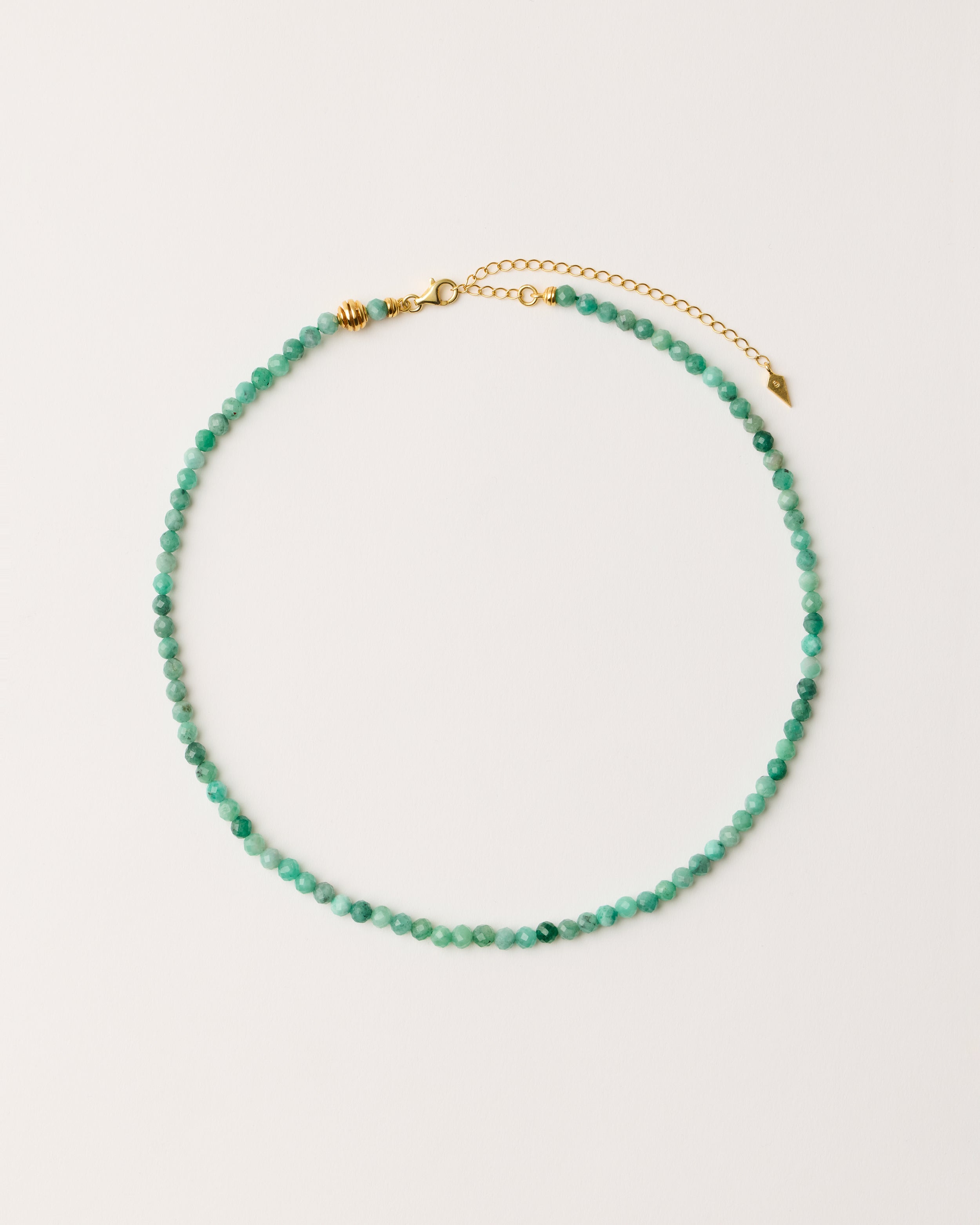 ETERNA VIRID Emerald necklace with polished gold-plated silver spiral bead, 8 cm extension chain and clasp, arrowhead-shaped fantasy signature, and 4 mm faceted emerald bead strand.