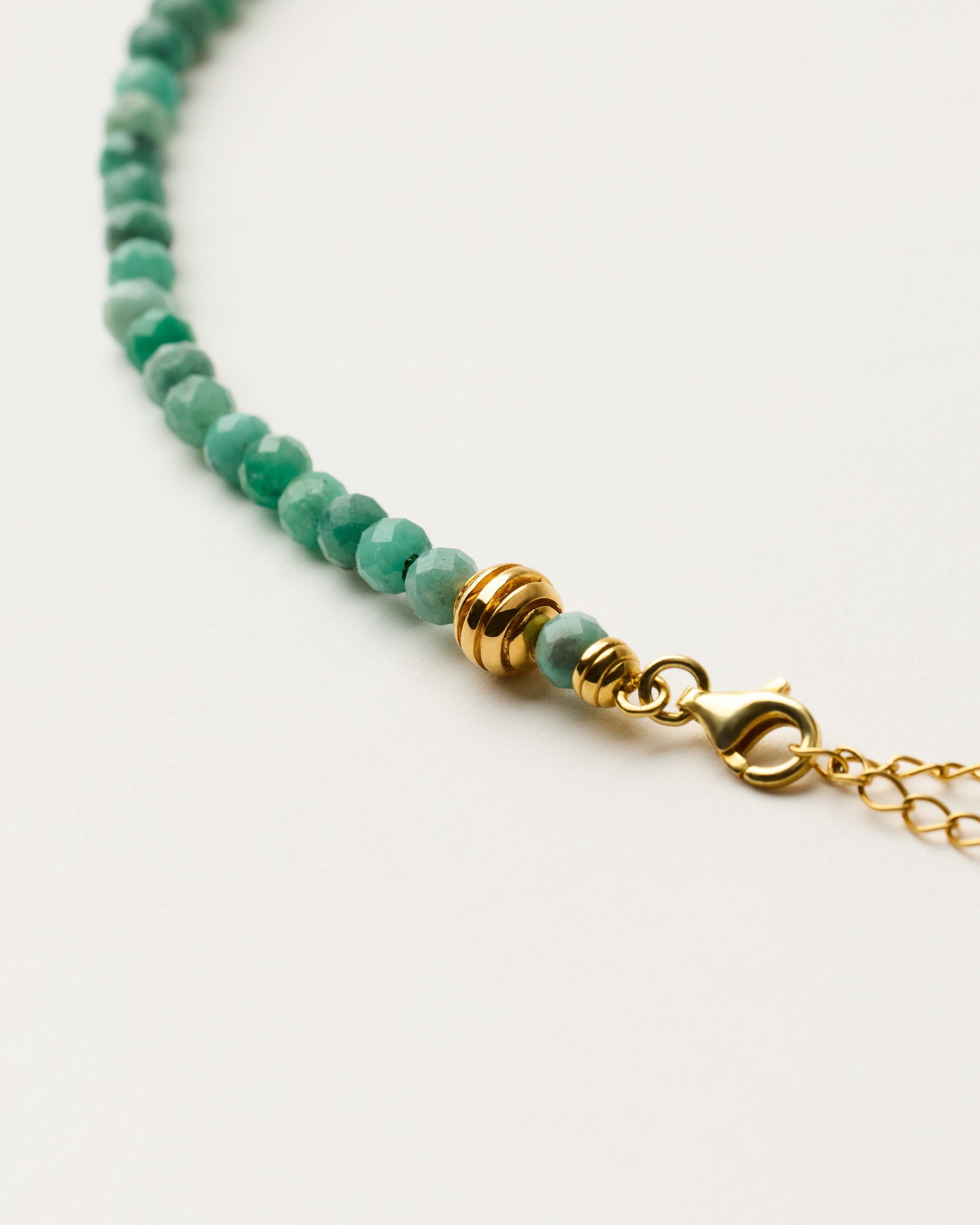 ETERNA VIRID Emerald necklace with polished gold-plated silver spiral bead, 8 cm extension chain and clasp, arrowhead-shaped fantasy signature, and 4 mm faceted emerald bead strand.
