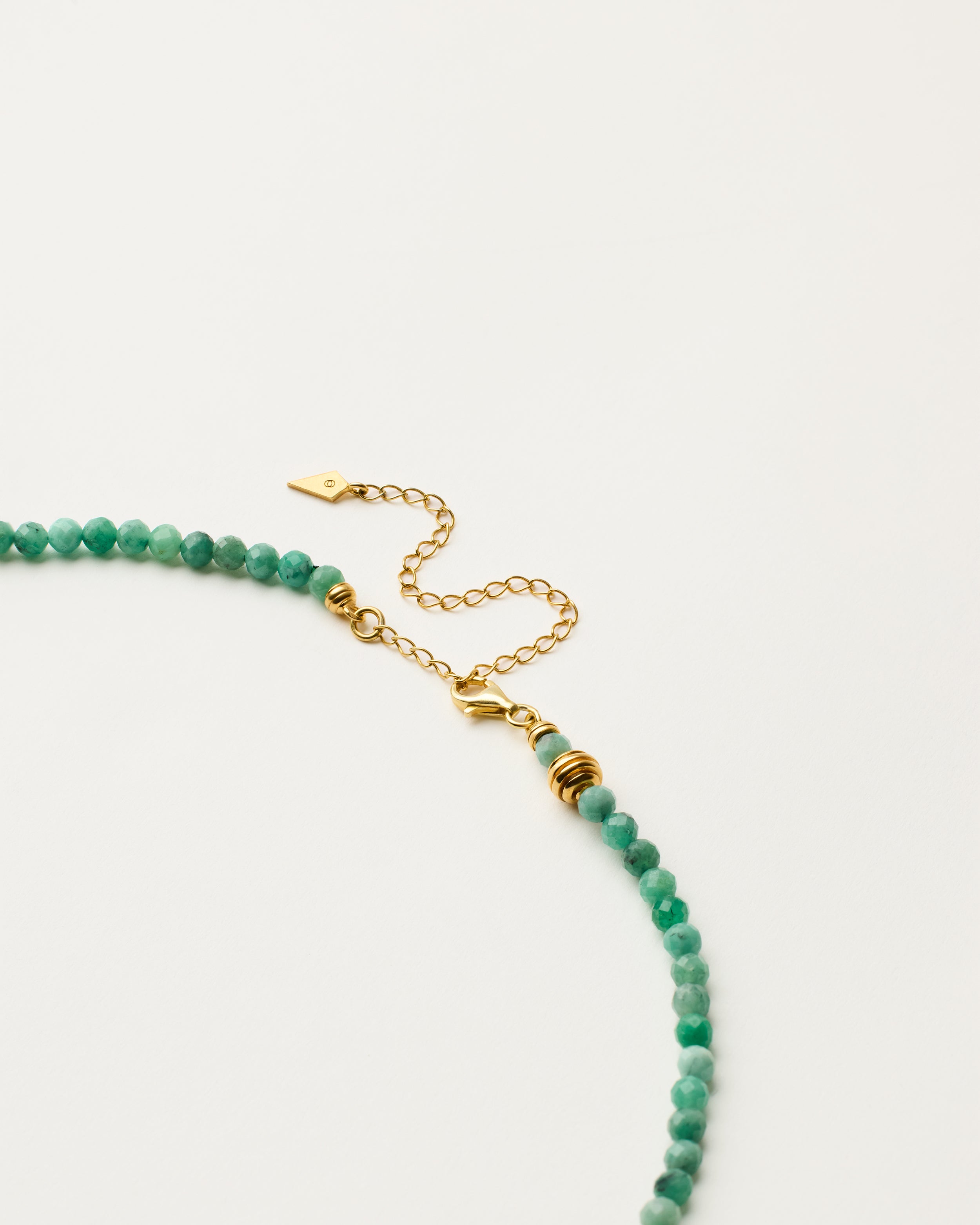 ETERNA VIRID Emerald necklace with polished gold-plated silver spiral bead, 8 cm extension chain and clasp, arrowhead-shaped fantasy signature, and 4 mm faceted emerald bead strand.