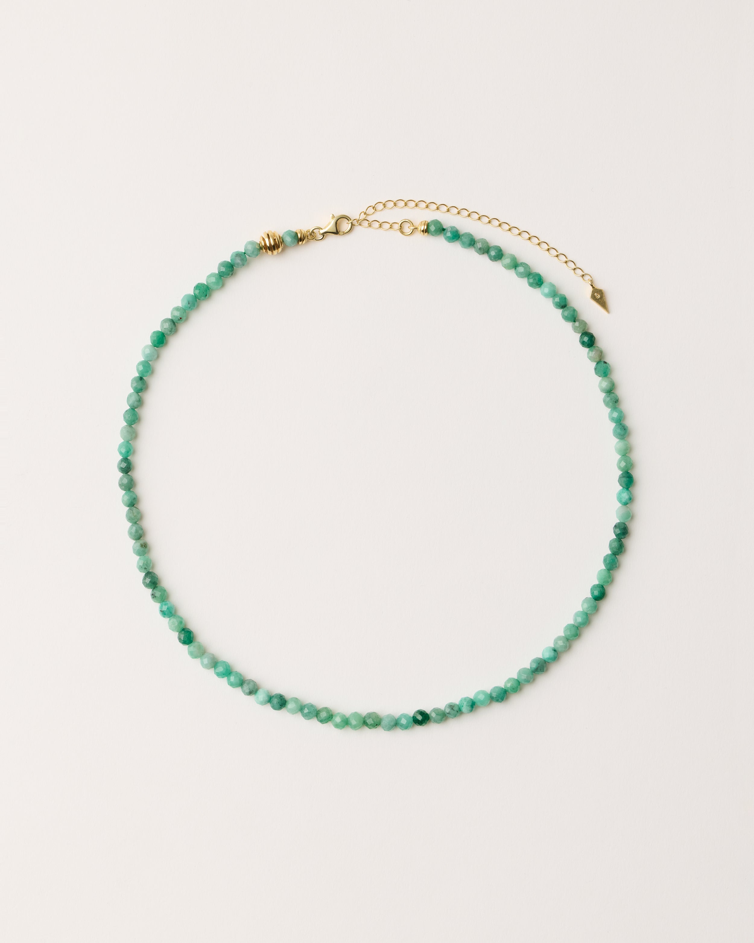 ETERNA VIRID Emerald necklace with polished gold spiral bead, 8 cm extension chain and clasp, arrowhead-shaped fantasy signature, and 4 mm faceted emerald bead strand.