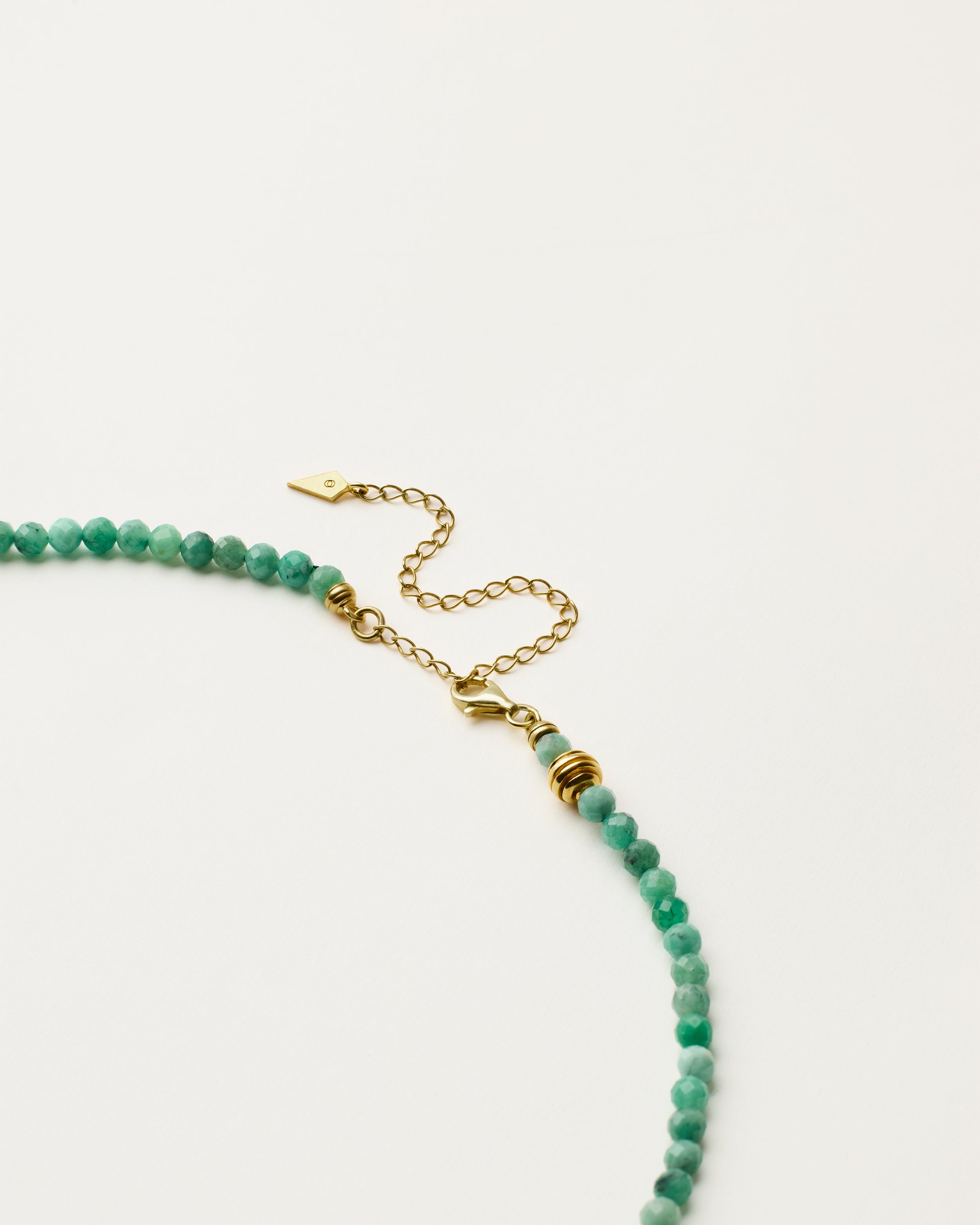 ETERNA VIRID Emerald necklace with polished gold spiral bead, 8 cm extension chain and clasp, arrowhead-shaped fantasy signature, and 4 mm faceted emerald bead strand.