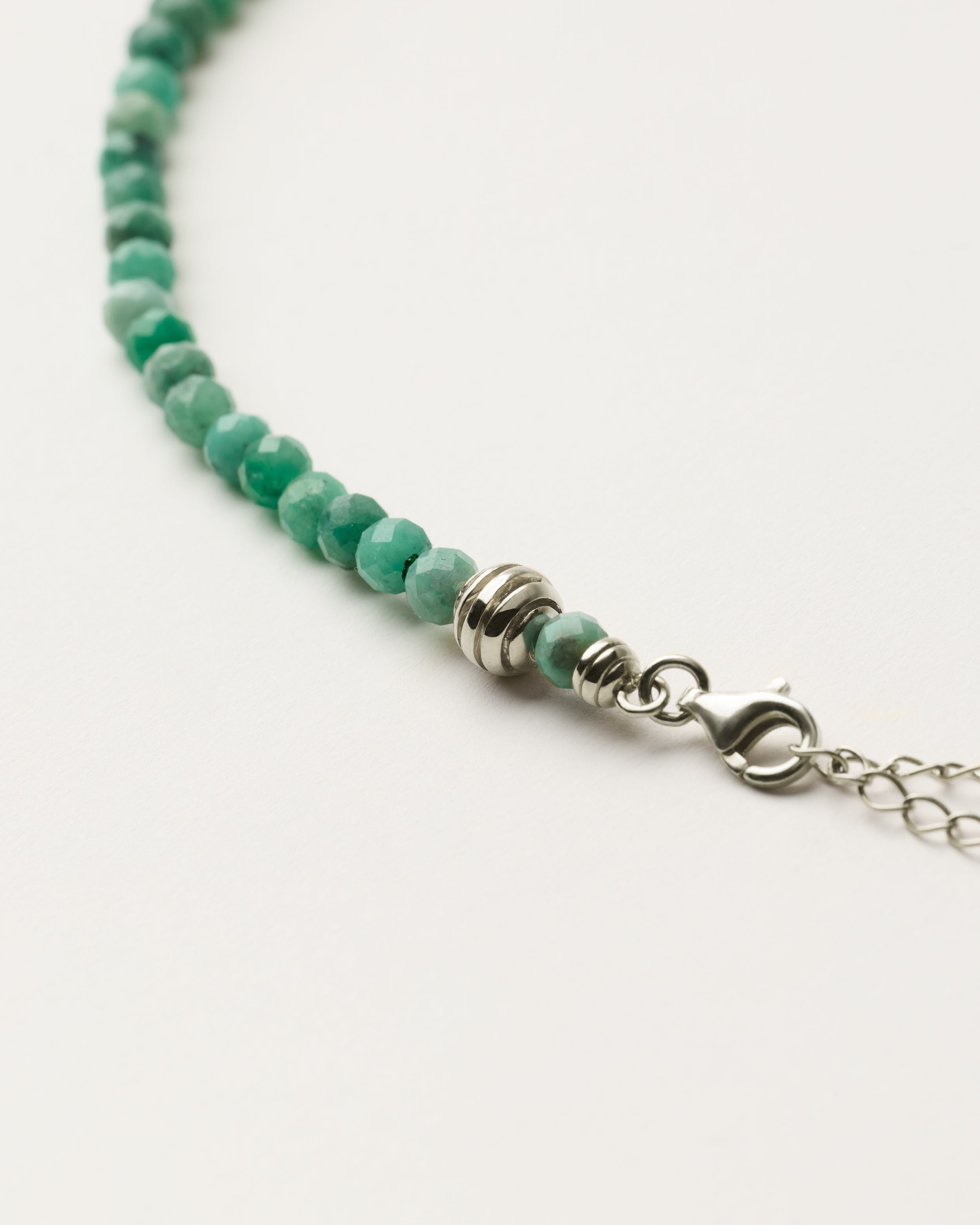 ETERNA VIRID Emerald necklace with polished silver spiral bead, 8 cm extension chain and clasp, arrowhead-shaped fantasy signature, and 4 mm faceted emerald bead strand.