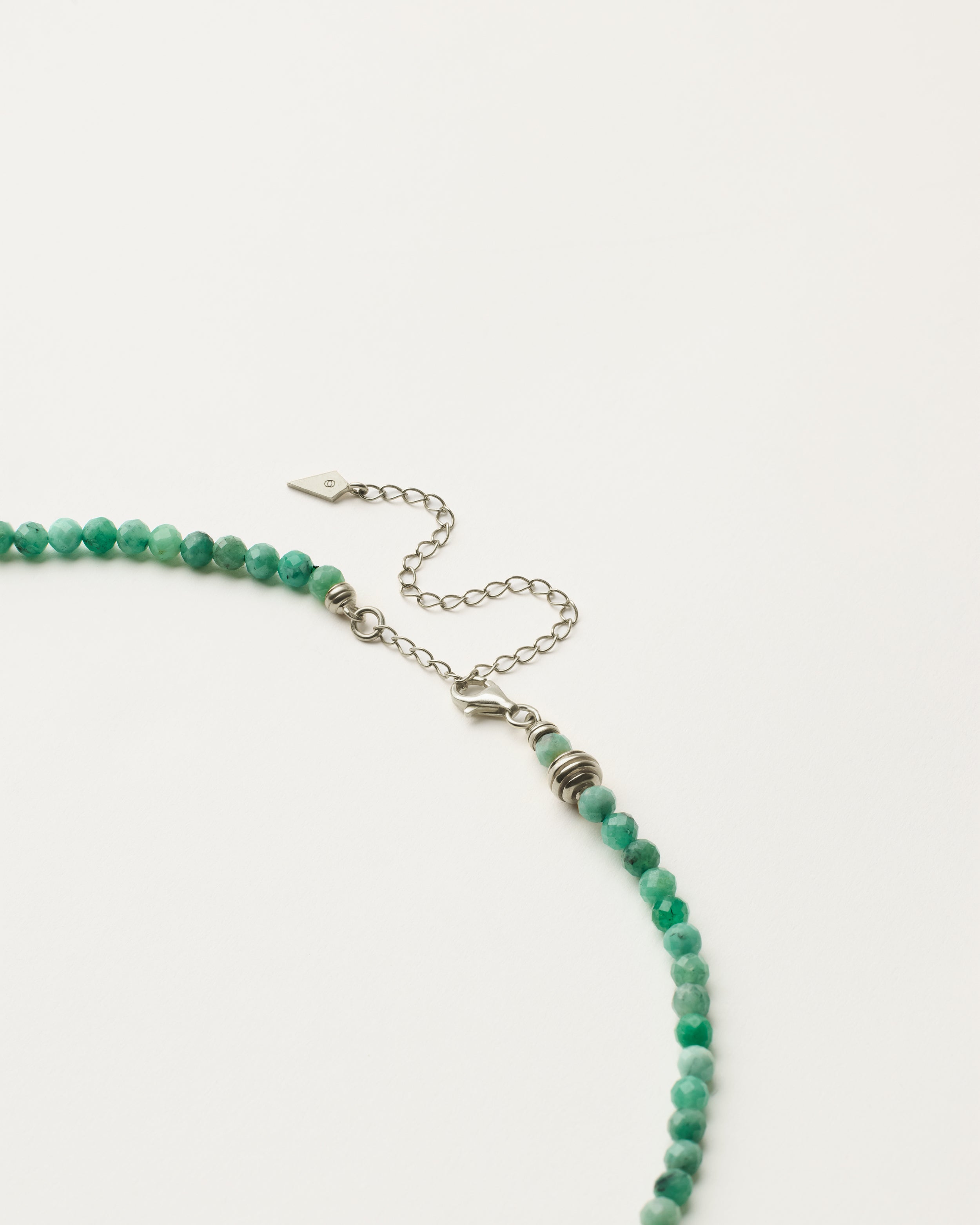 ETERNA VIRID Emerald necklace with polished silver spiral bead, 8 cm extension chain and clasp, arrowhead-shaped fantasy signature, and 4 mm faceted emerald bead strand.