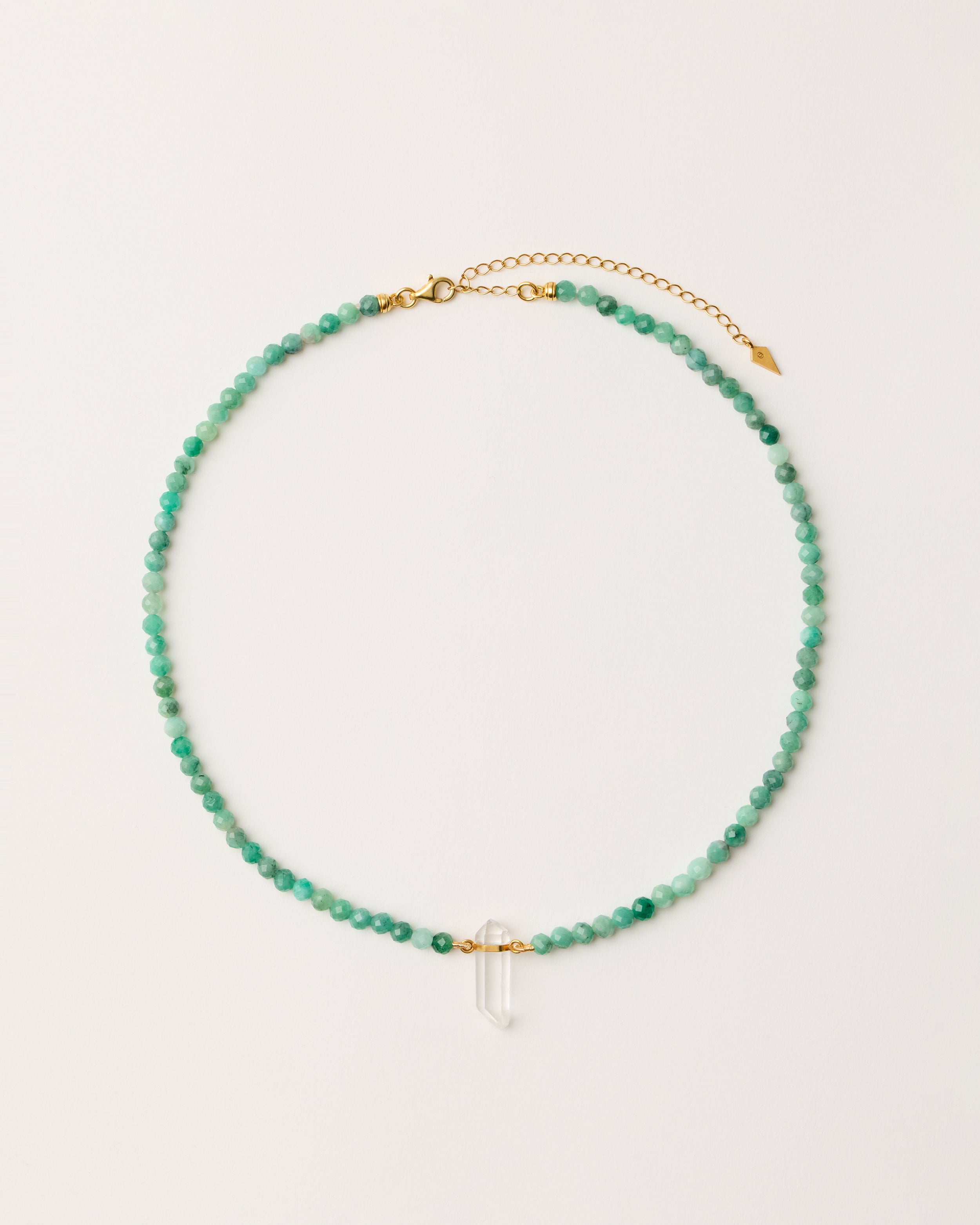ENCARA VIRID Emerald necklace with raw polished quartz point pendant, gold-plated silver 8 cm extension chain and clasp, arrowhead-shaped fantasy signature, and 4 mm faceted emerald bead strand.