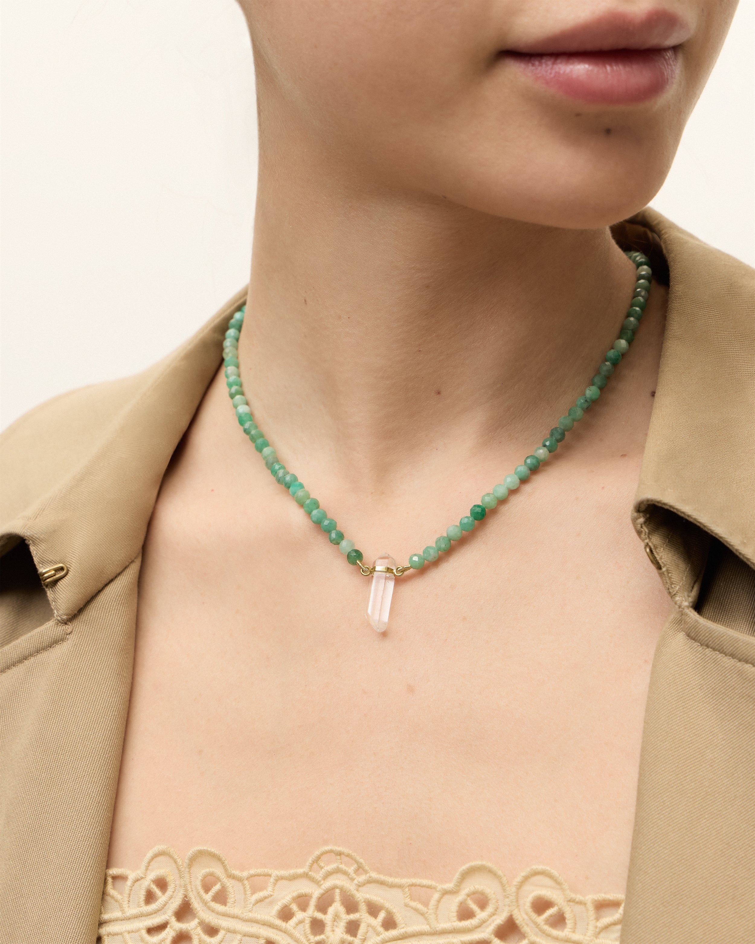 ENCARA VIRID Emerald necklace with raw polished quartz point pendant, gold 8 cm extension chain and clasp, arrowhead-shaped fantasy signature, and 4 mm faceted emerald bead strand.