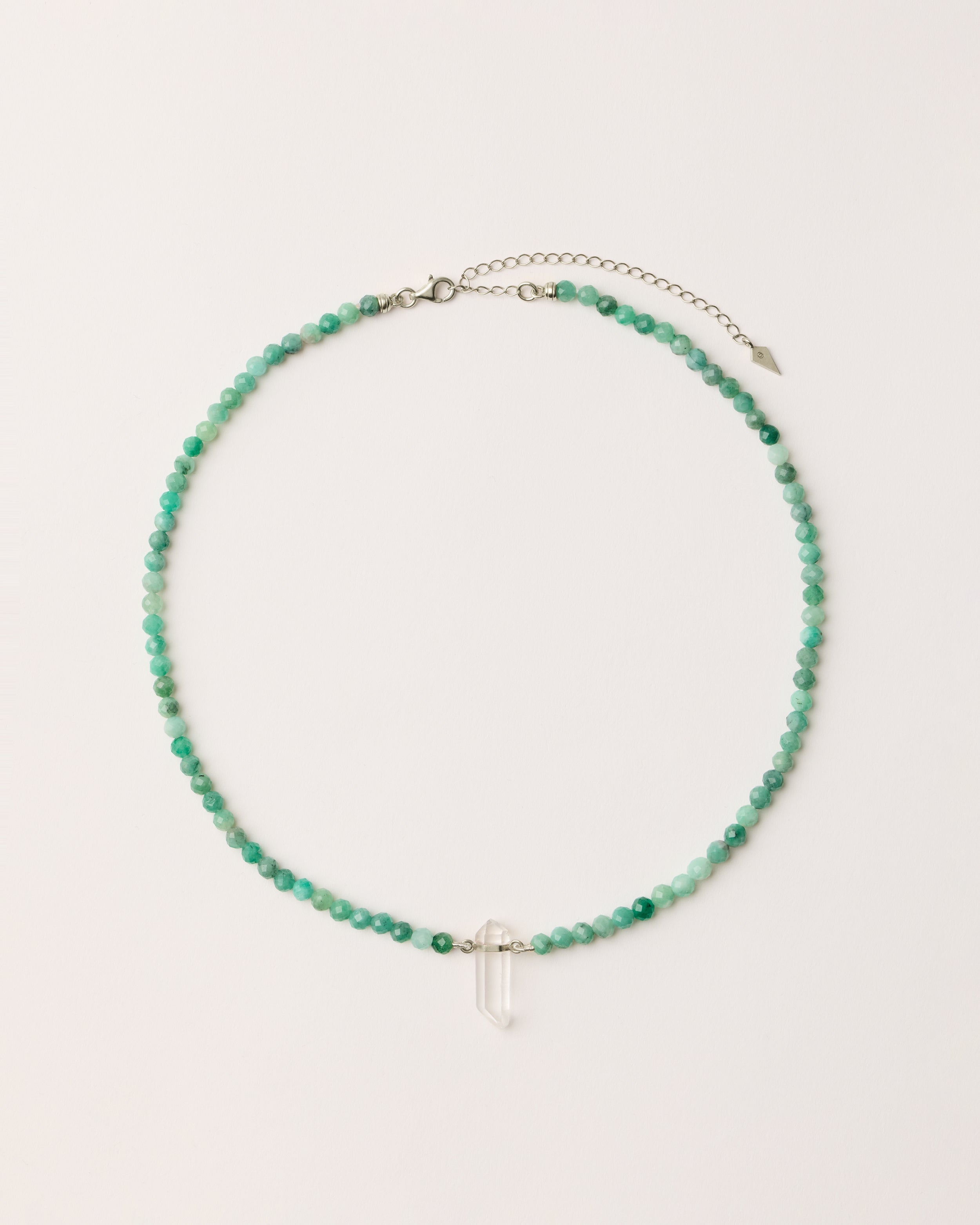 ENCARA VIRID Emerald necklace with raw polished quartz point pendant, silver 8 cm extension chain and clasp, arrowhead-shaped fantasy signature, and 4 mm faceted emerald bead strand.