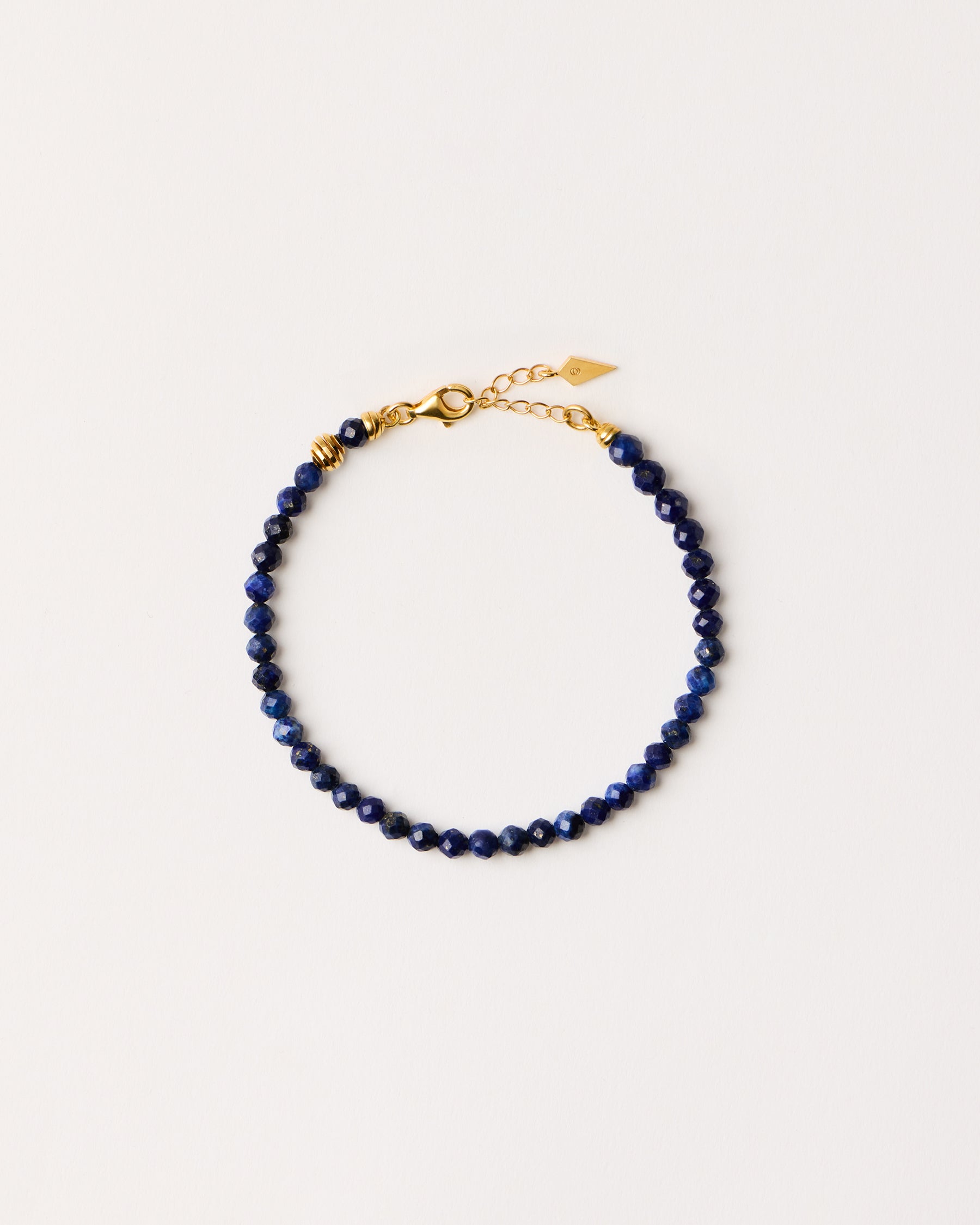ETERNA NOCTA Lapis Lazuli necklace with polished gold-plated silver spiral bead, 8 cm extension chain and clasp, arrowhead-shaped fantasy signature, and 4 mm faceted lazurite bead strand.