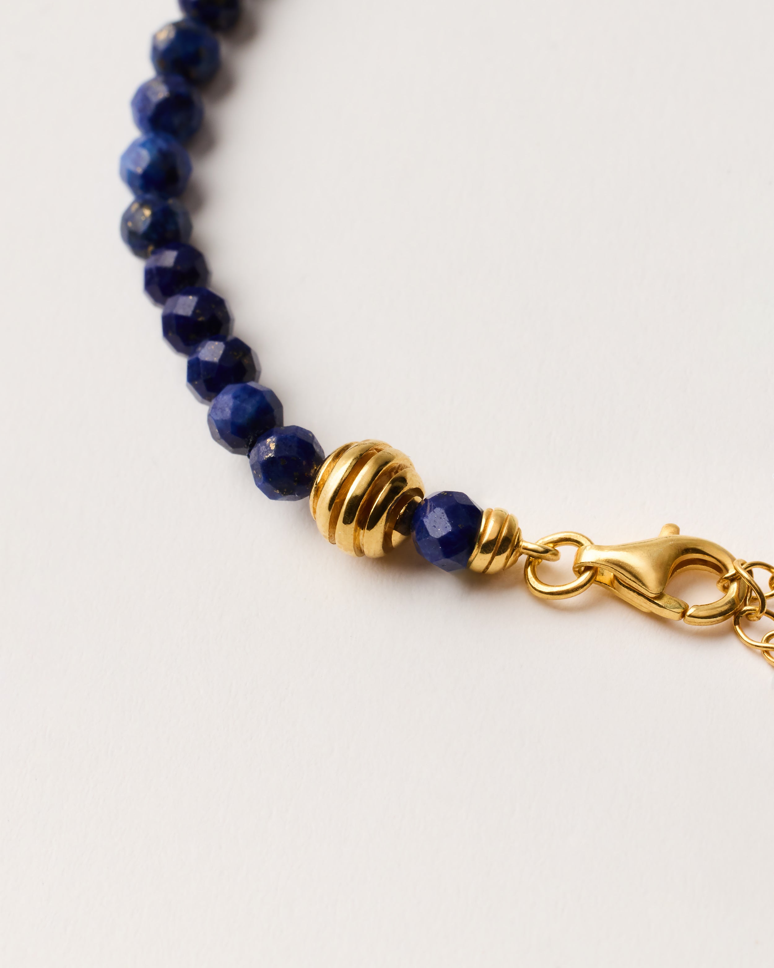 ETERNA NOCTA Lapis Lazuli necklace with polished gold-plated silver spiral bead, 8 cm extension chain and clasp, arrowhead-shaped fantasy signature, and 4 mm faceted lazurite bead strand.