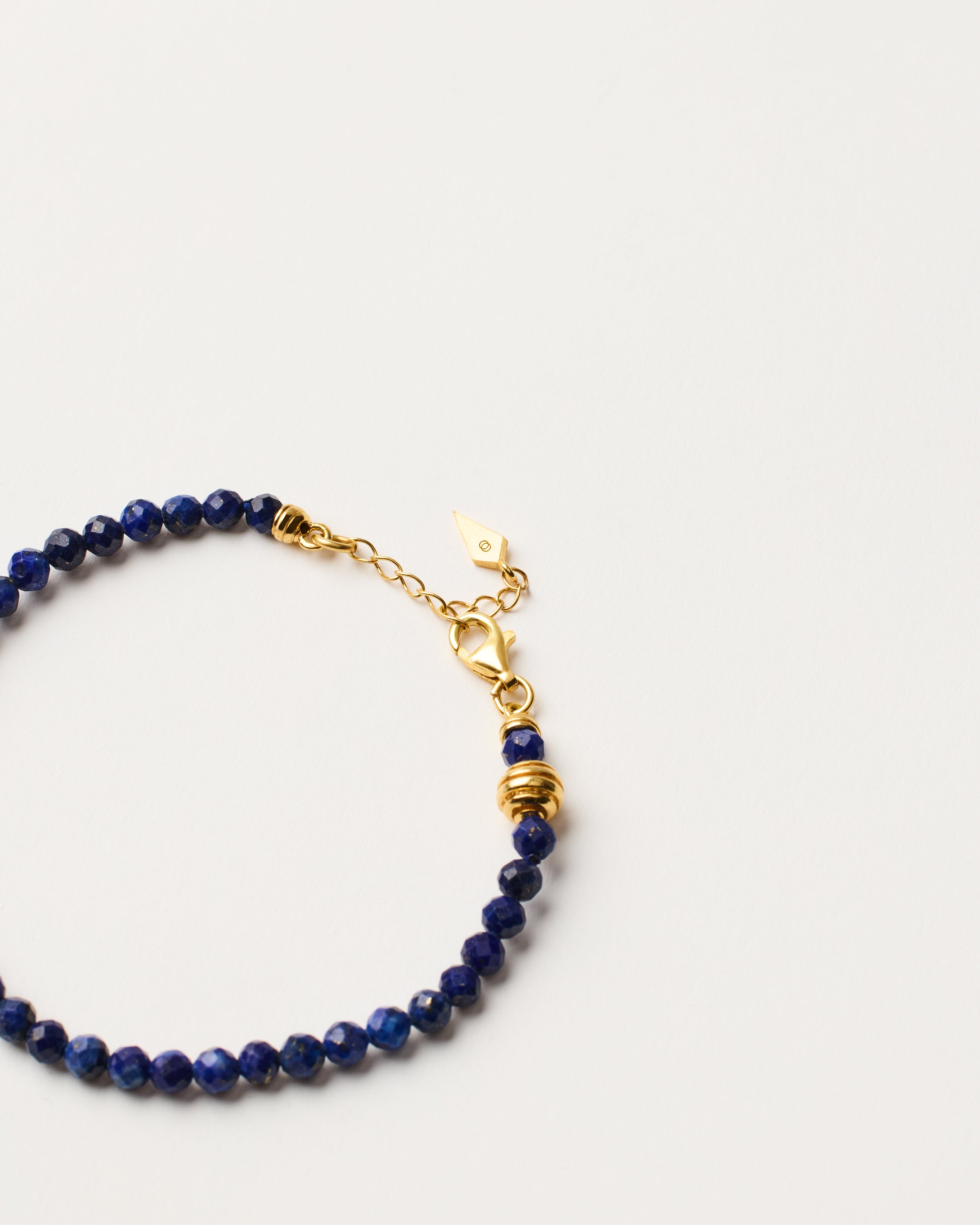 ETERNA NOCTA Lapis Lazuli necklace with polished gold-plated silver spiral bead, 8 cm extension chain and clasp, arrowhead-shaped fantasy signature, and 4 mm faceted lazurite bead strand.