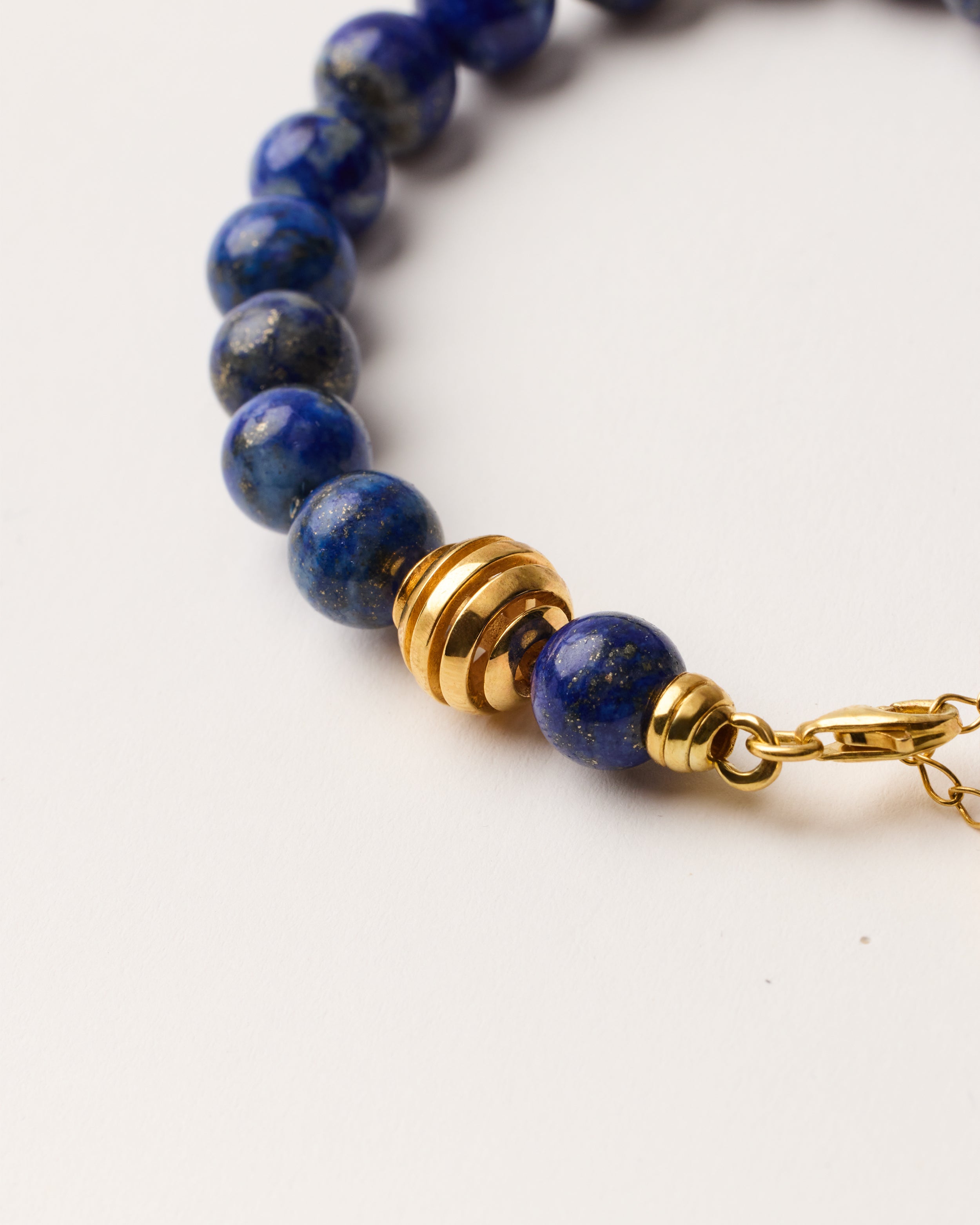 ETERNA NOCTA Lapis Lazuli necklace with polished gold-plated silver spiral bead, 8 cm extension chain and clasp, arrowhead-shaped fantasy signature, and 8 mm faceted lazurite bead strand.
