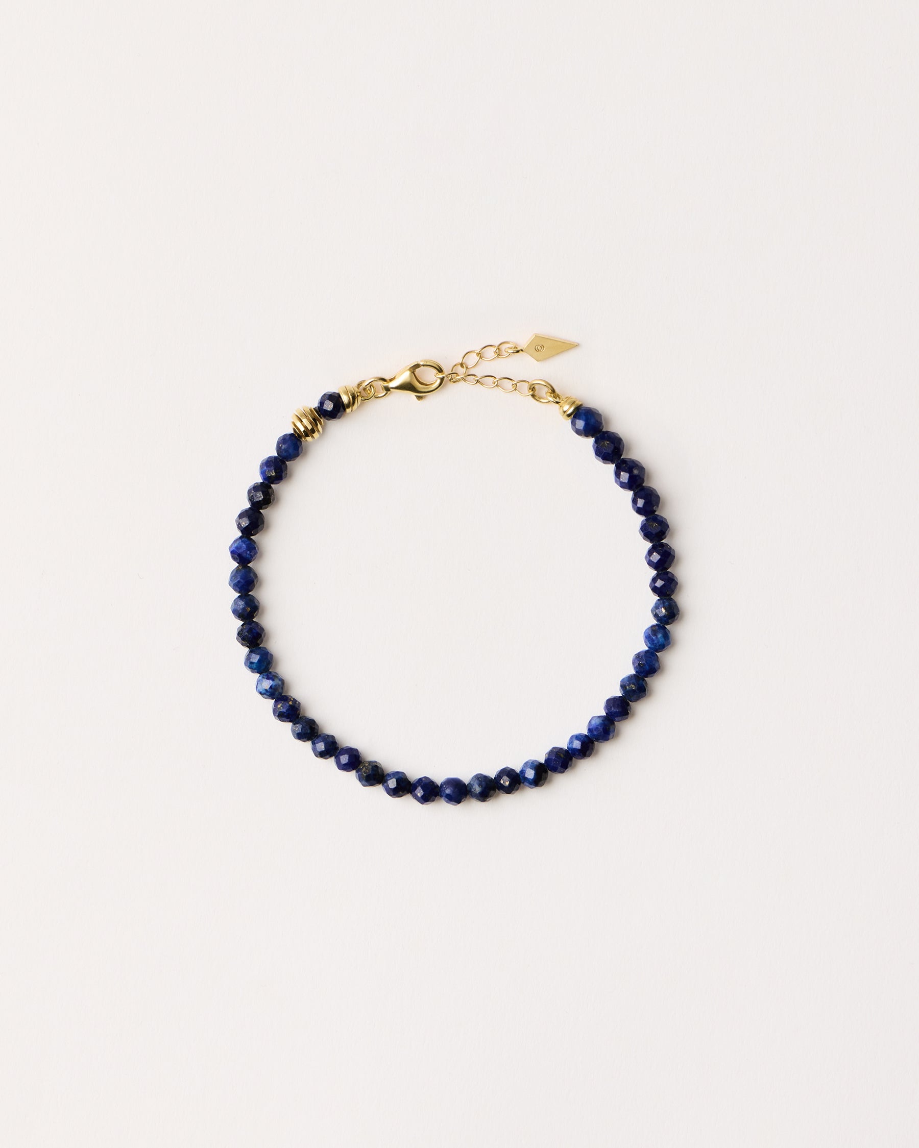 ETERNA NOCTA Lapis Lazuli necklace with polished gold spiral bead, 8 cm extension chain and clasp, arrowhead-shaped fantasy signature, and 4 mm faceted lazurite bead strand.