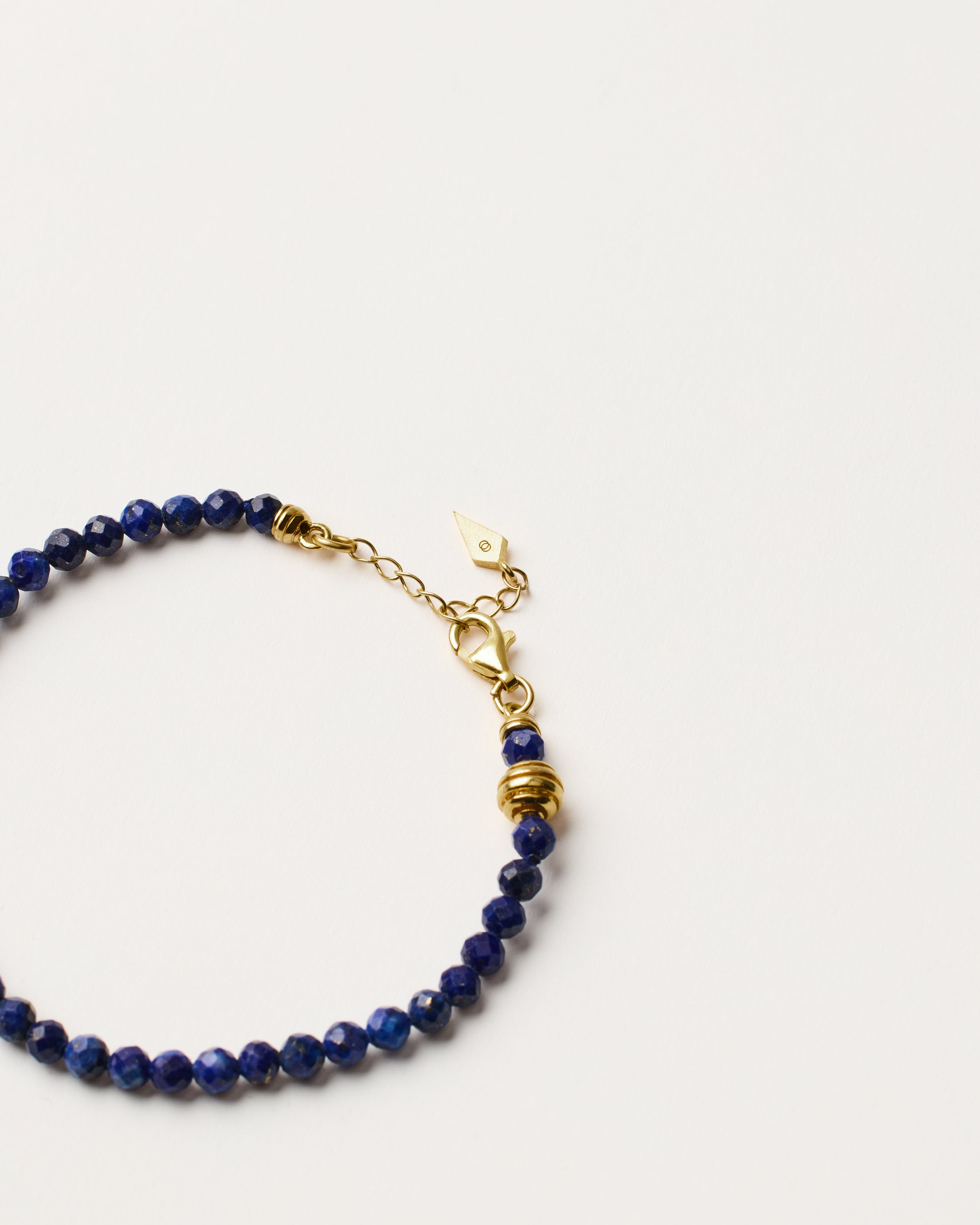 ETERNA NOCTA Lapis Lazuli necklace with polished gold spiral bead, 8 cm extension chain and clasp, arrowhead-shaped fantasy signature, and 4 mm faceted lazurite bead strand.