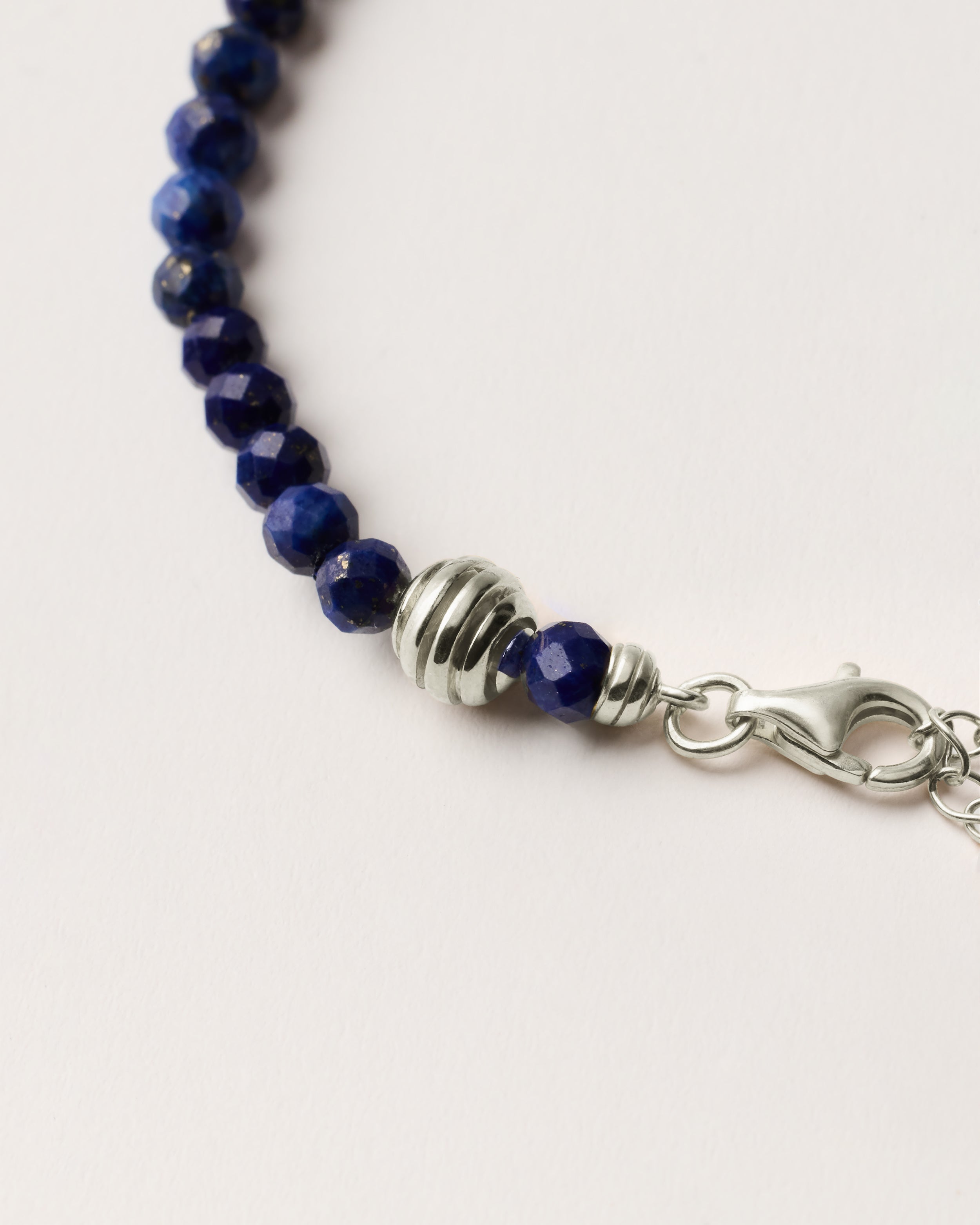 ETERNA NOCTA Lapis Lazuli necklace with polished silver spiral bead, 8 cm extension chain and clasp, arrowhead-shaped fantasy signature, and 4 mm faceted lazurite bead strand.