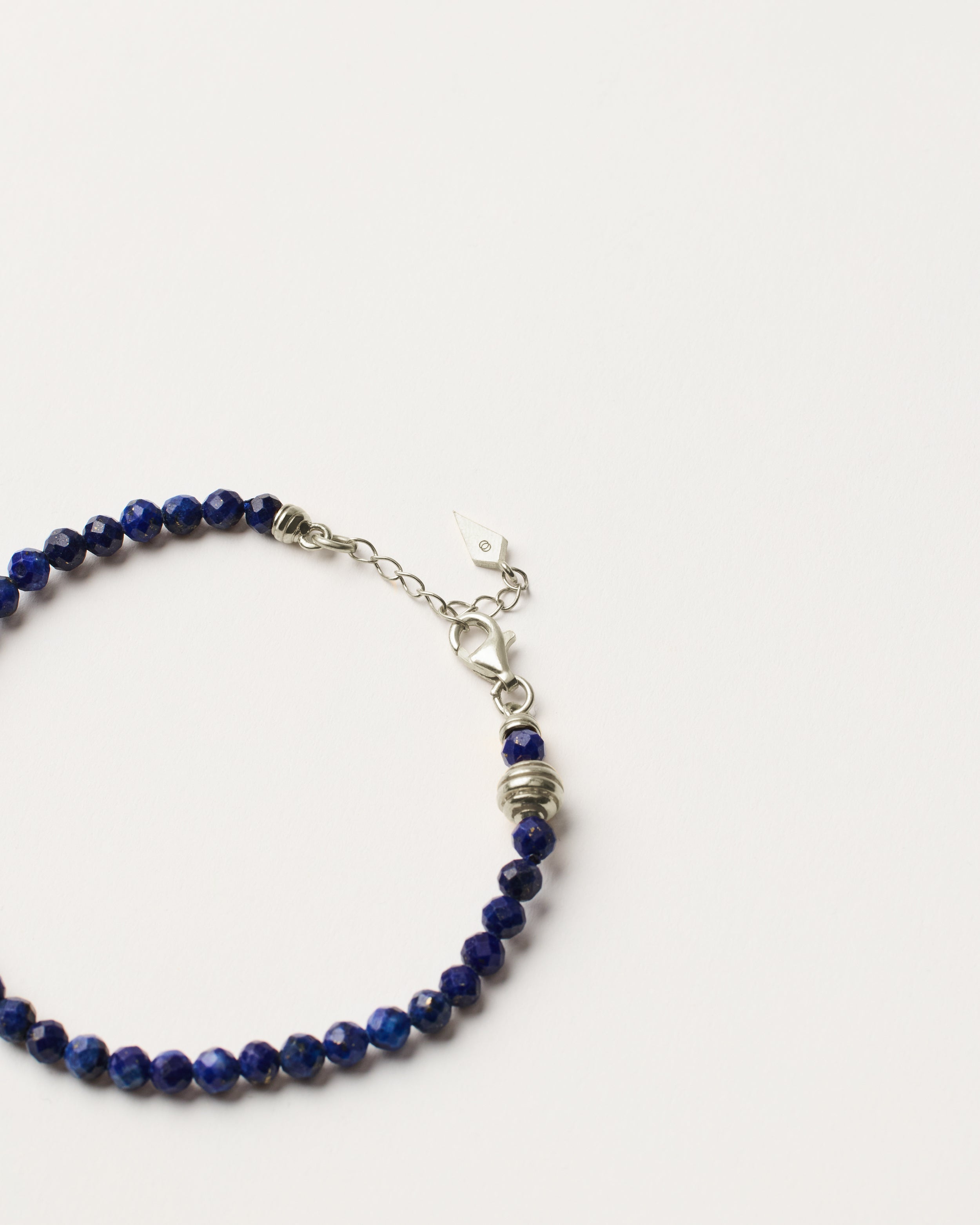 ETERNA NOCTA Lapis Lazuli necklace with polished silver spiral bead, 8 cm extension chain and clasp, arrowhead-shaped fantasy signature, and 4 mm faceted lazurite bead strand.