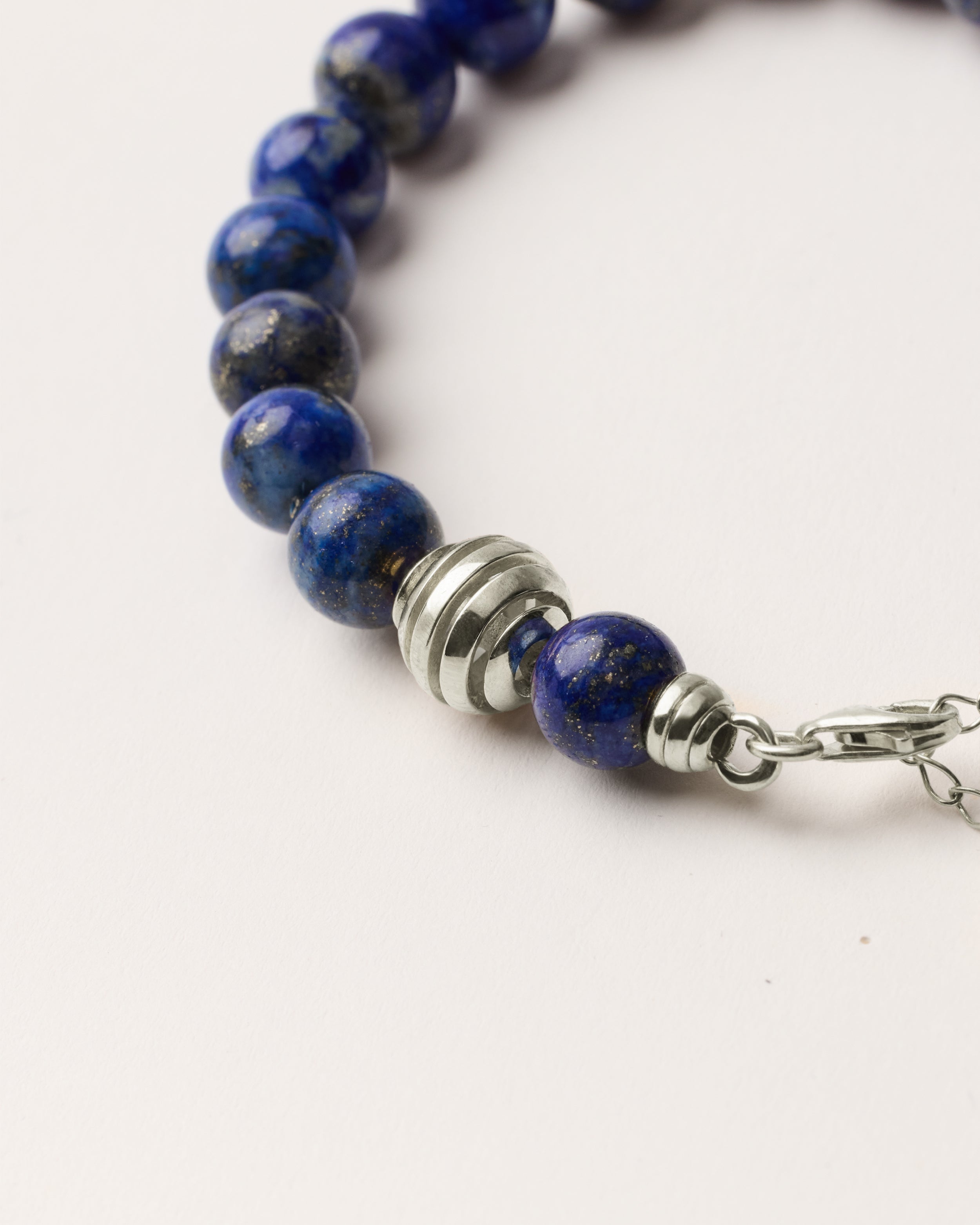 ETERNA NOCTA Lapis Lazuli necklace with polished silver spiral bead, 8 cm extension chain and clasp, arrowhead-shaped fantasy signature, and 8 mm faceted lazurite bead strand.