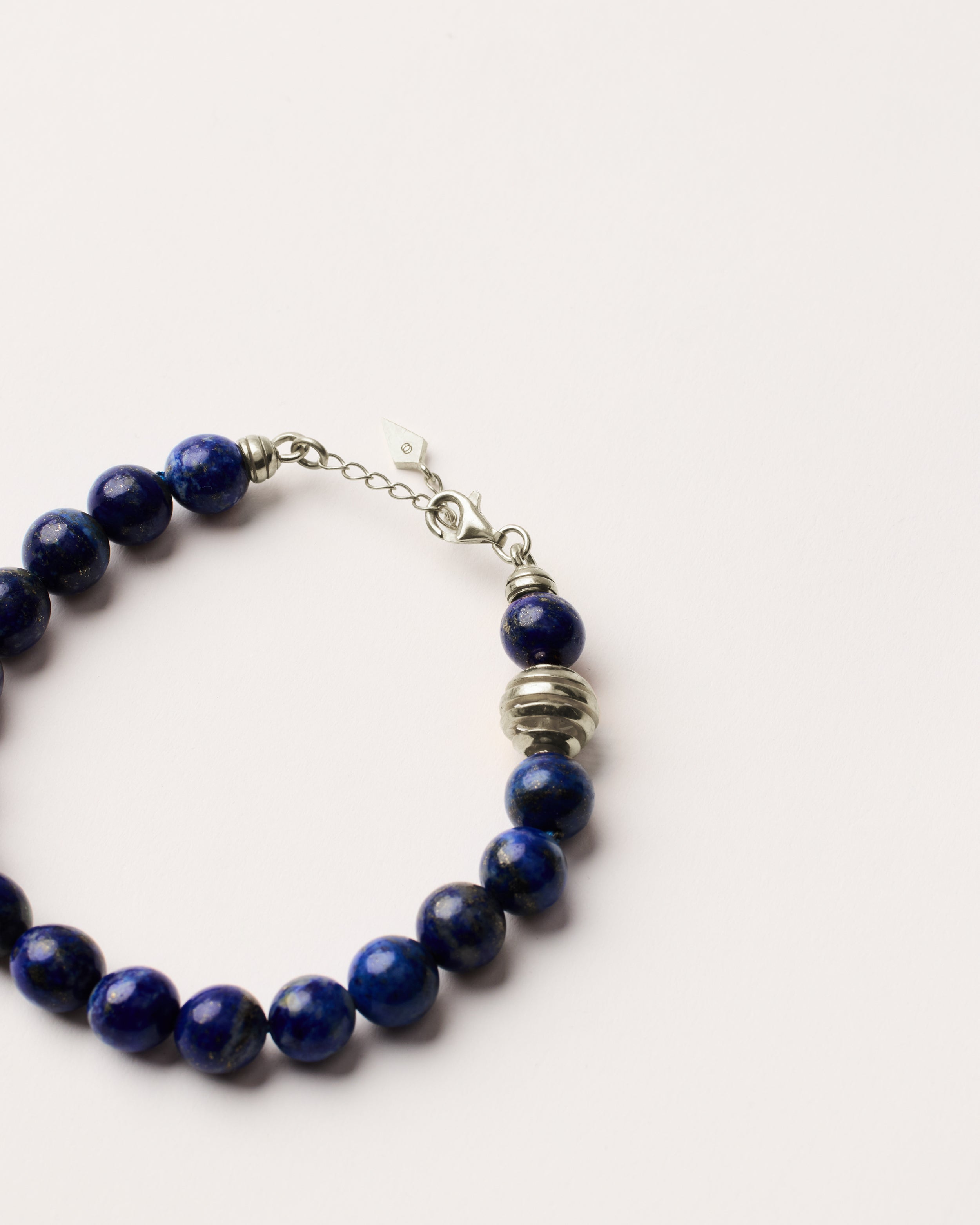 ETERNA NOCTA Lapis Lazuli necklace with polished silver spiral bead, 8 cm extension chain and clasp, arrowhead-shaped fantasy signature, and 8 mm faceted lazurite bead strand.