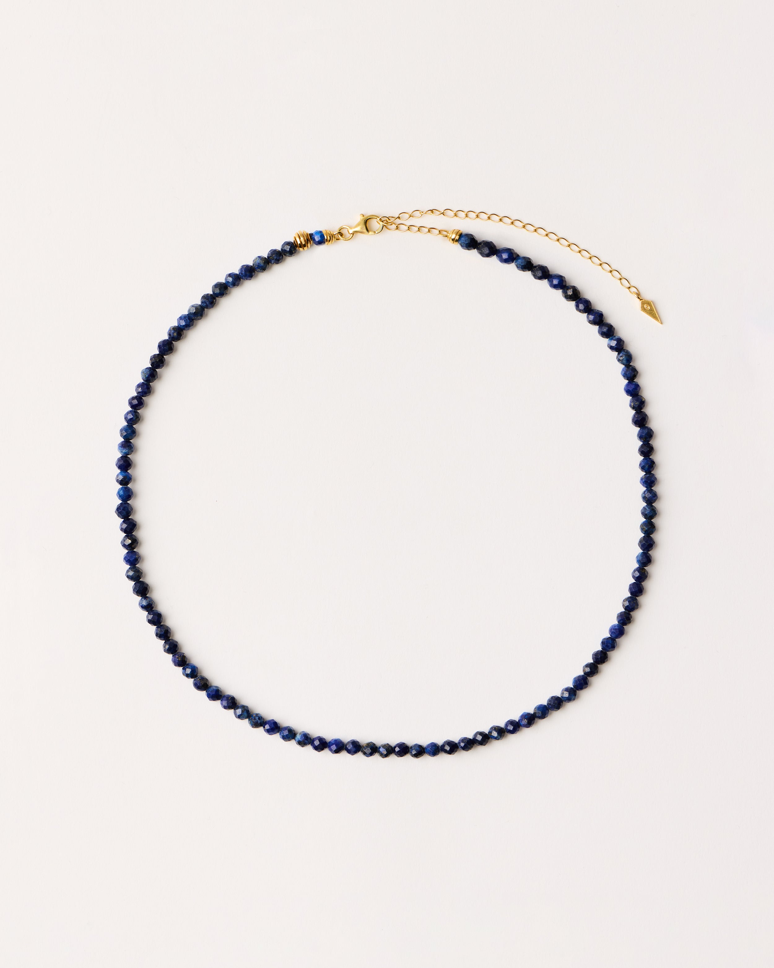 ENCARA NOCTA Lapis Lazuli necklace with raw polished quartz point pendant, gold-plated silver 8 cm extension chain and clasp, arrowhead-shaped fantasy signature, and 4 mm faceted lazurite bead strand.