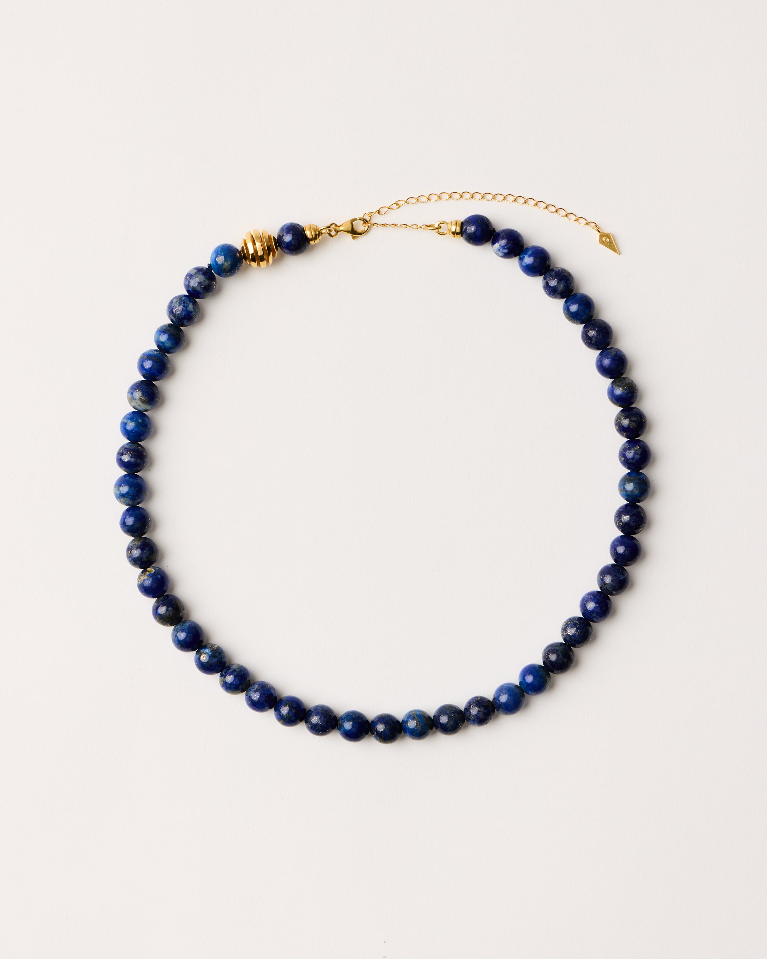 ENCARA NOCTA Lapis Lazuli necklace with raw polished quartz point pendant, gold-plated silver 8 cm extension chain and clasp, arrowhead-shaped fantasy signature, and 8 mm faceted lazurite bead strand.