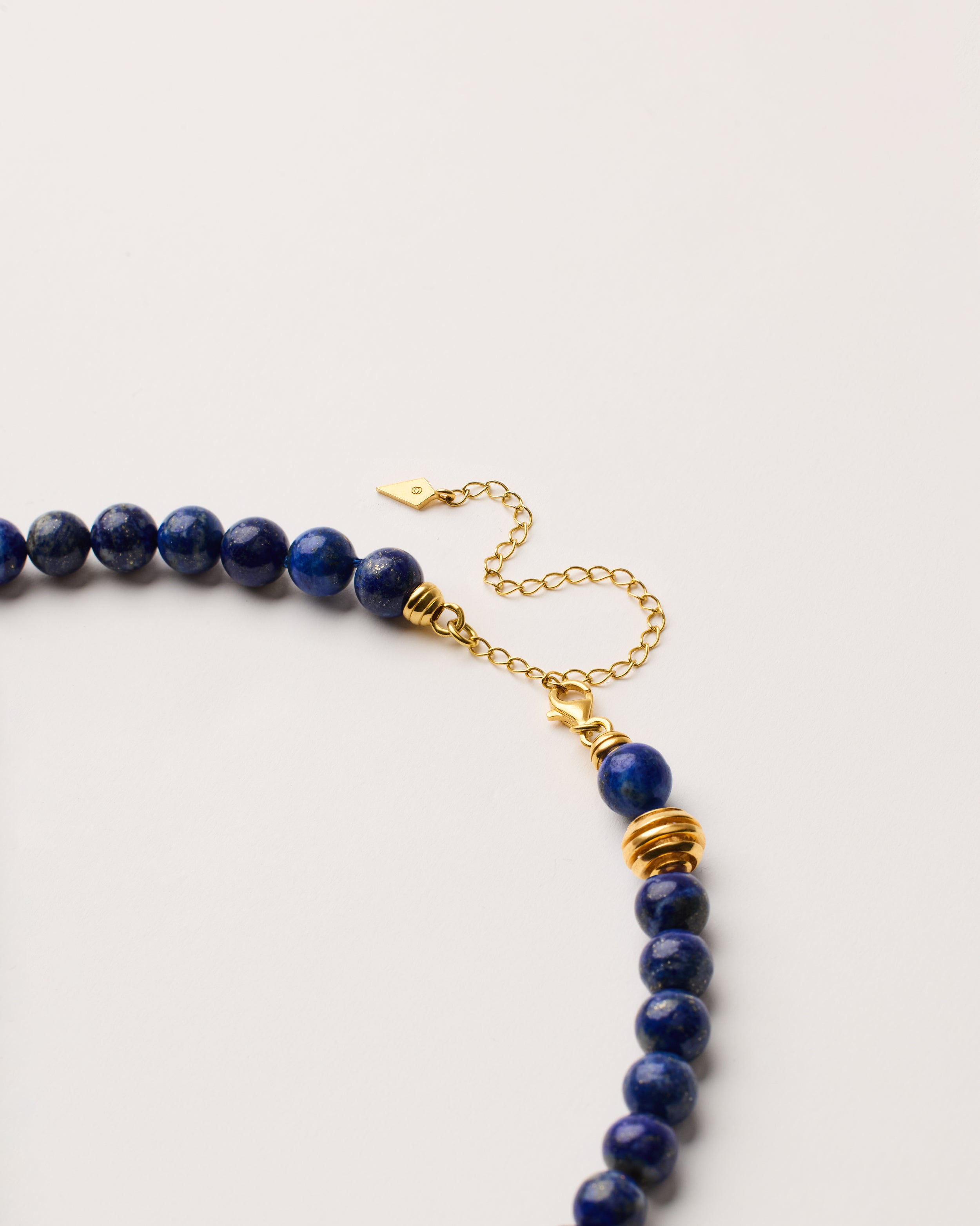 ETERNA NOCTA Lapis Lazuli necklace with polished gold-plated silver spiral bead, 8 cm extension chain and clasp, arrowhead-shaped fantasy signature, and 8 mm faceted lazurite bead strand.