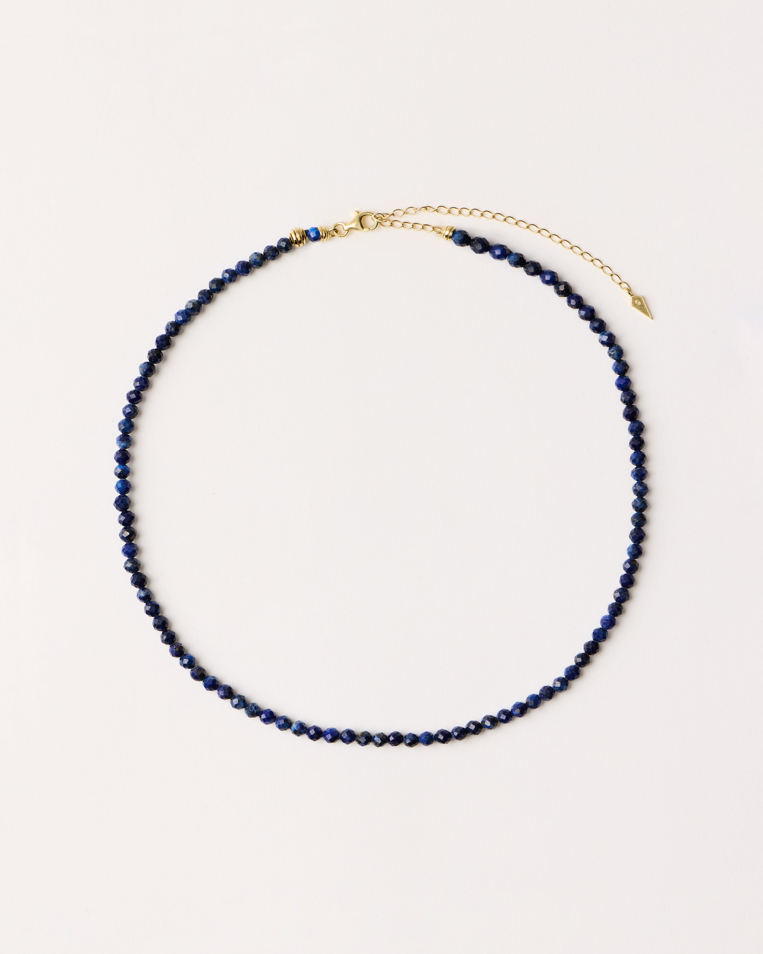 ETERNA NOCTA Lapis Lazuli necklace with polished gold spiral bead, 8 cm extension chain and clasp, arrowhead-shaped fantasy signature, and 4 mm faceted lazurite bead strand.