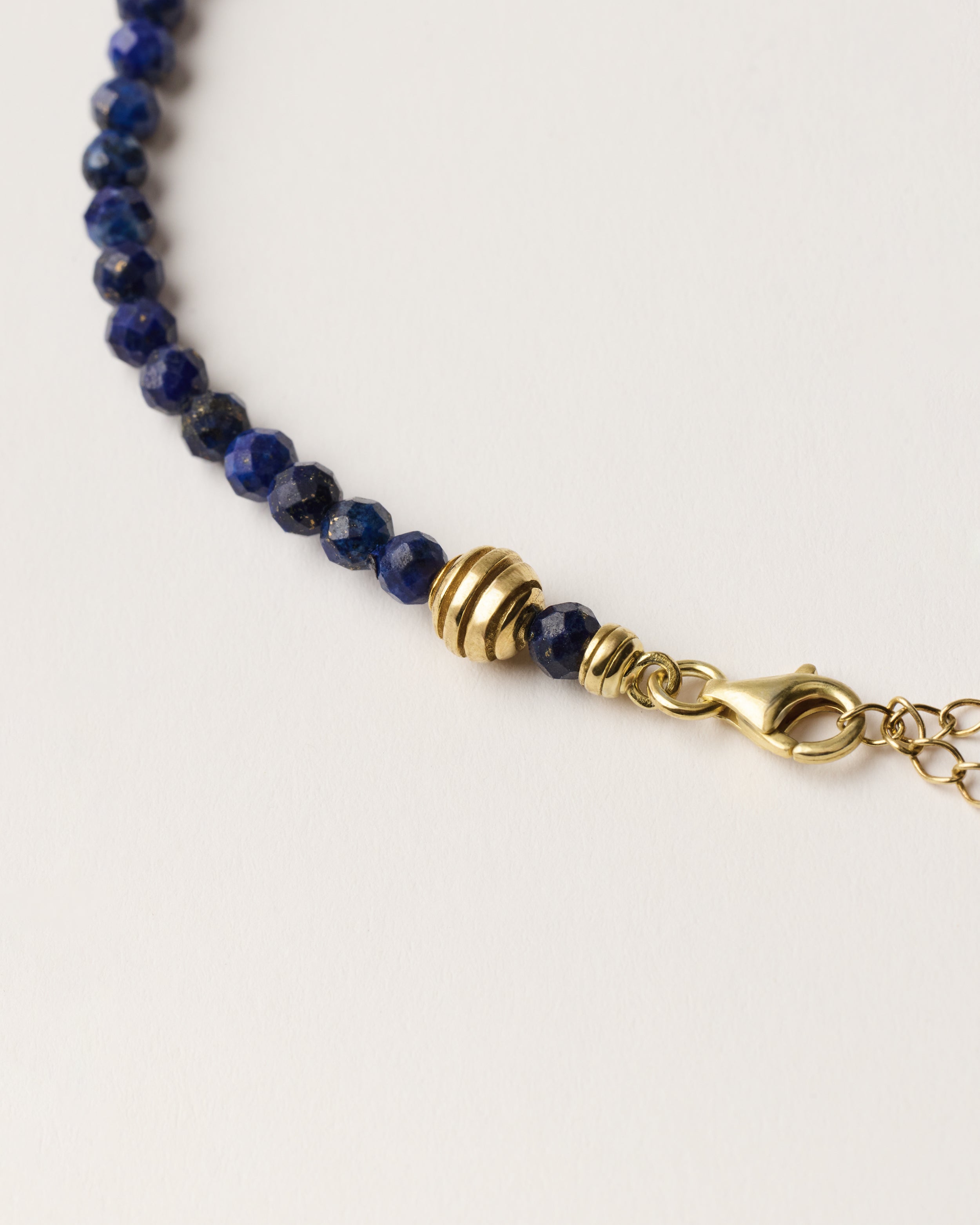 ETERNA NOCTA Lapis Lazuli necklace with polished gold spiral bead, 8 cm extension chain and clasp, arrowhead-shaped fantasy signature, and 4 mm faceted lazurite bead strand.