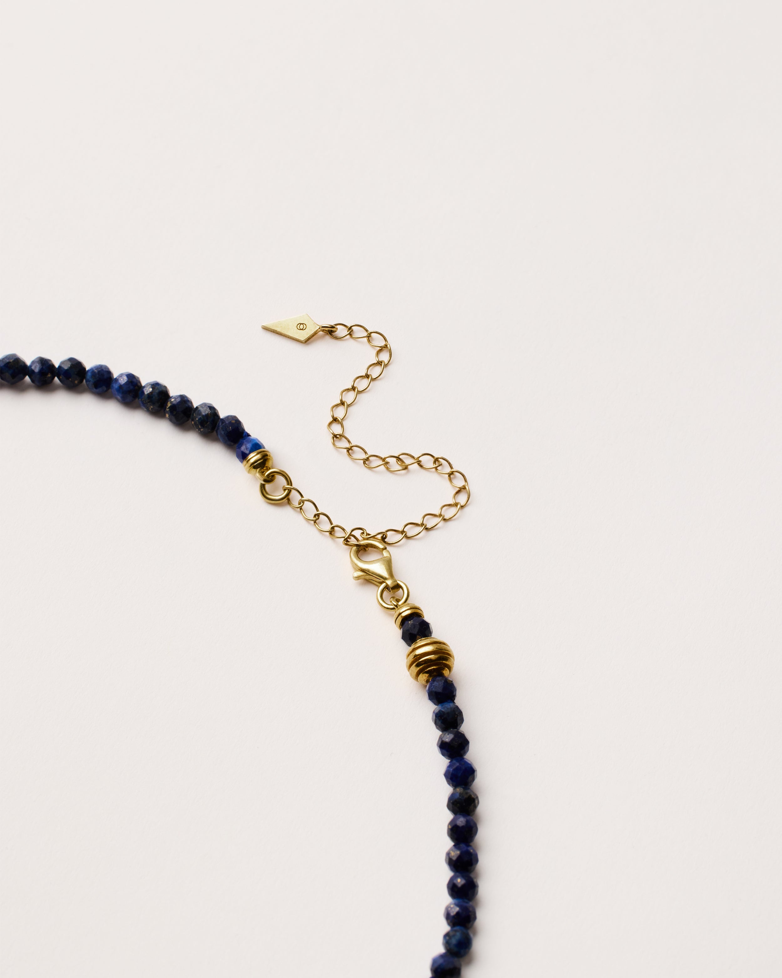 ETERNA NOCTA Lapis Lazuli necklace with polished gold spiral bead, 8 cm extension chain and clasp, arrowhead-shaped fantasy signature, and 4 mm faceted lazurite bead strand.