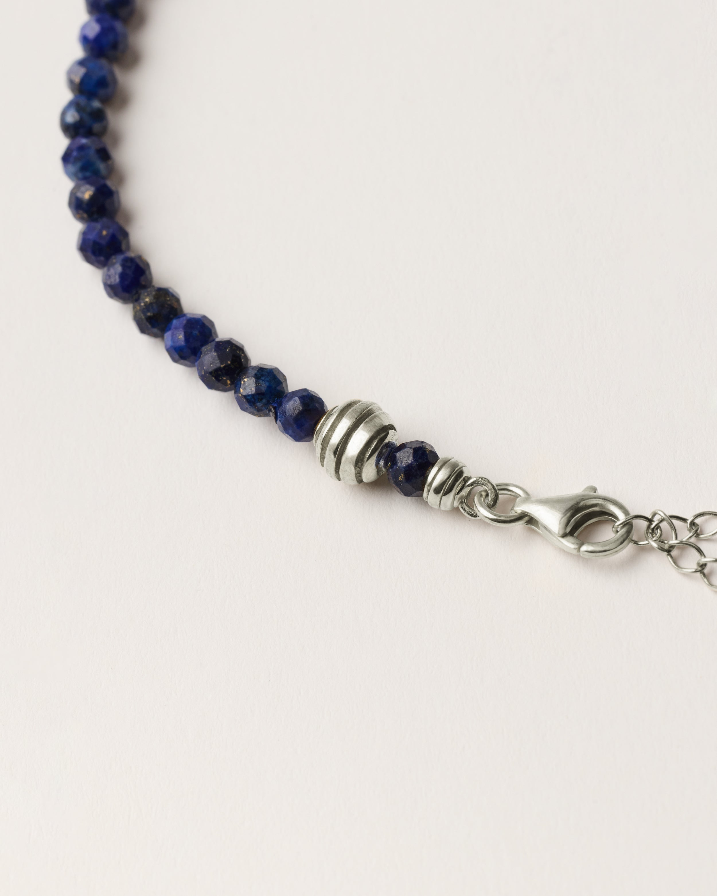 ETERNA NOCTA Lapis Lazuli necklace with polished silver spiral bead, 8 cm extension chain and clasp, arrowhead-shaped fantasy signature, and 4 mm faceted lazurite bead strand.