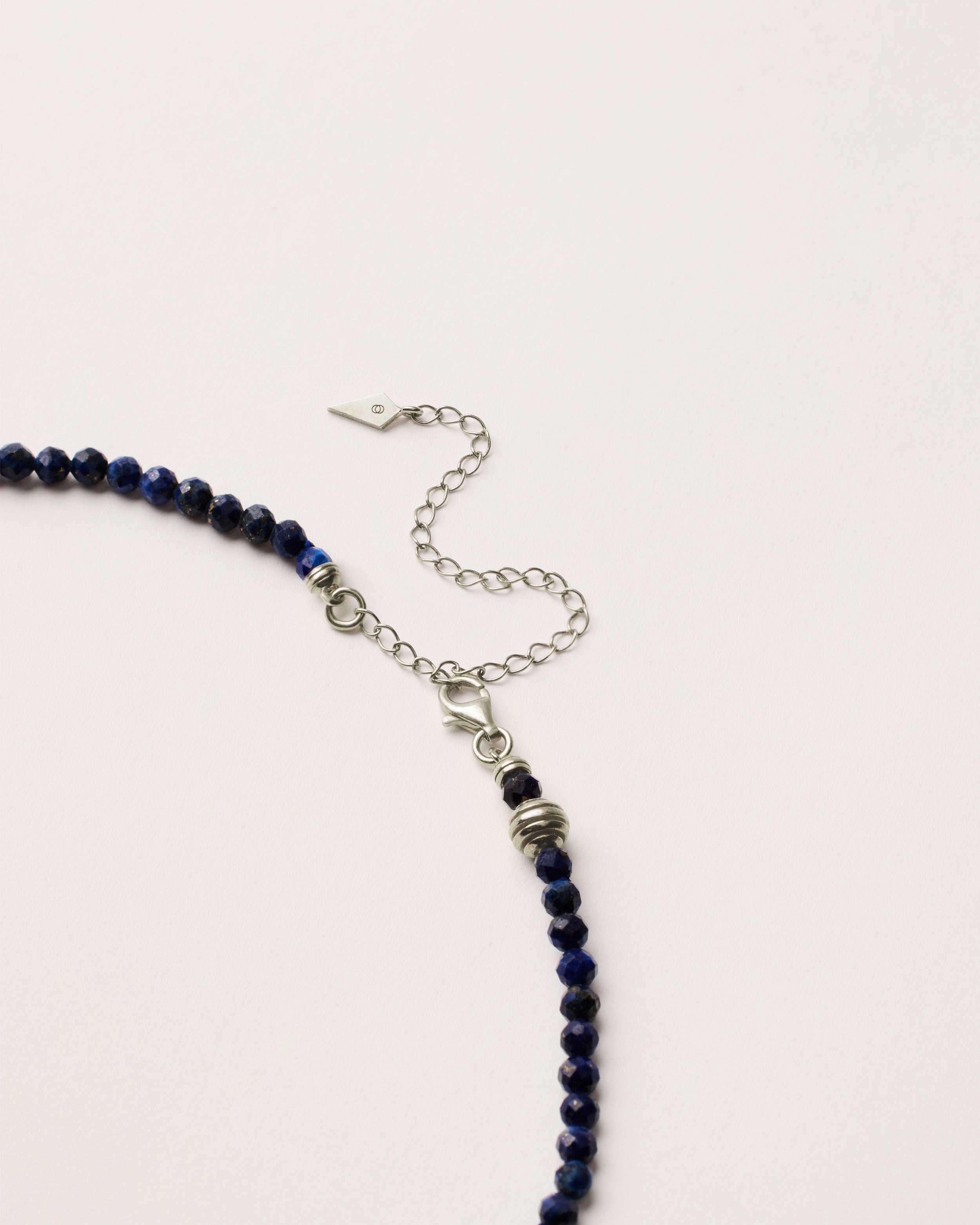 ETERNA NOCTA Lapis Lazuli necklace with polished silver spiral bead, 8 cm extension chain and clasp, arrowhead-shaped fantasy signature, and 4 mm faceted lazurite bead strand.
