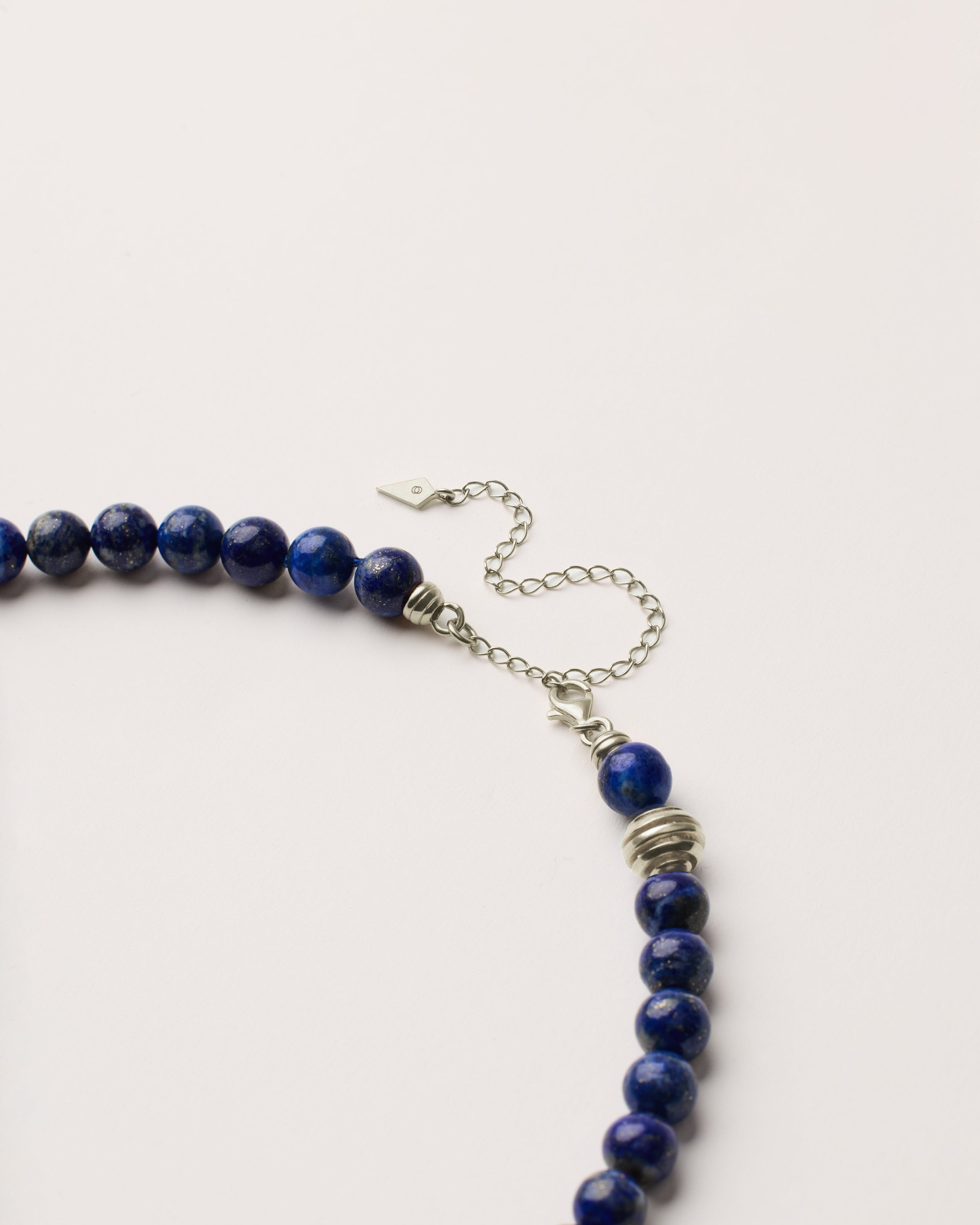 ETERNA NOCTA Lapis Lazuli necklace with polished silver spiral bead, 8 cm extension chain and clasp, arrowhead-shaped fantasy signature, and 8 mm faceted lazurite bead strand.