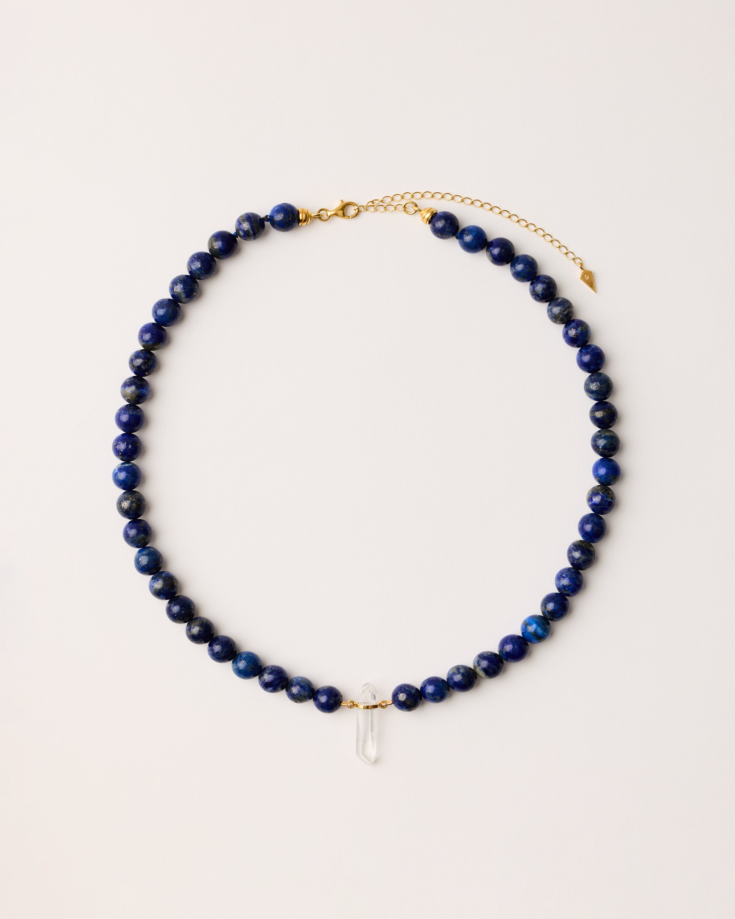 ENCARA NOCTA Lapis Lazuli necklace with raw polished quartz point pendant, gold-plated silver 8 cm extension chain and clasp, arrowhead-shaped fantasy signature, and 8 mm faceted lazurite bead strand.