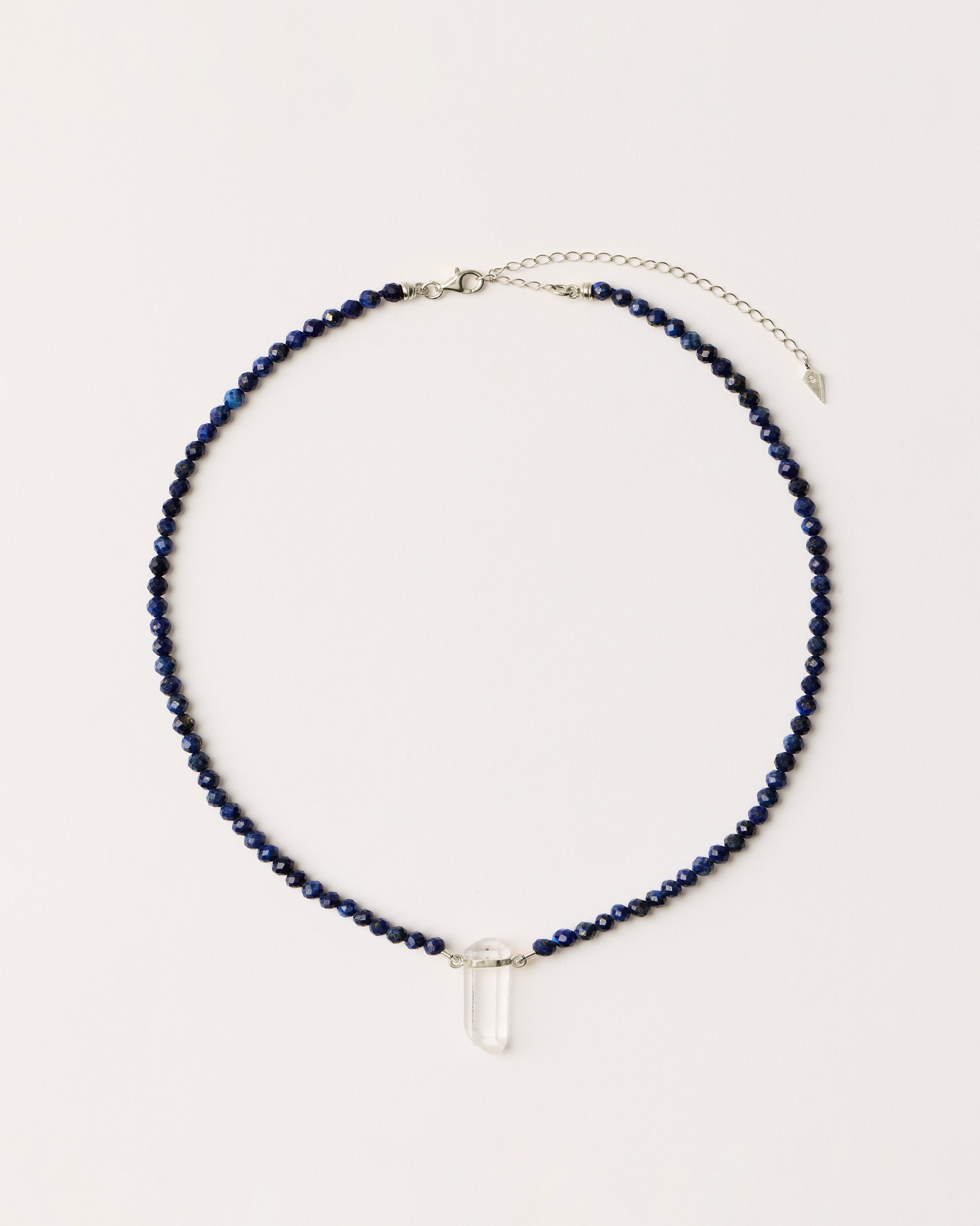 ENCARA NOCTA Lapis Lazuli necklace with raw polished quartz point pendant, silver 8 cm extension chain and clasp, arrowhead-shaped fantasy signature, and 4 mm faceted lazurite bead strand.