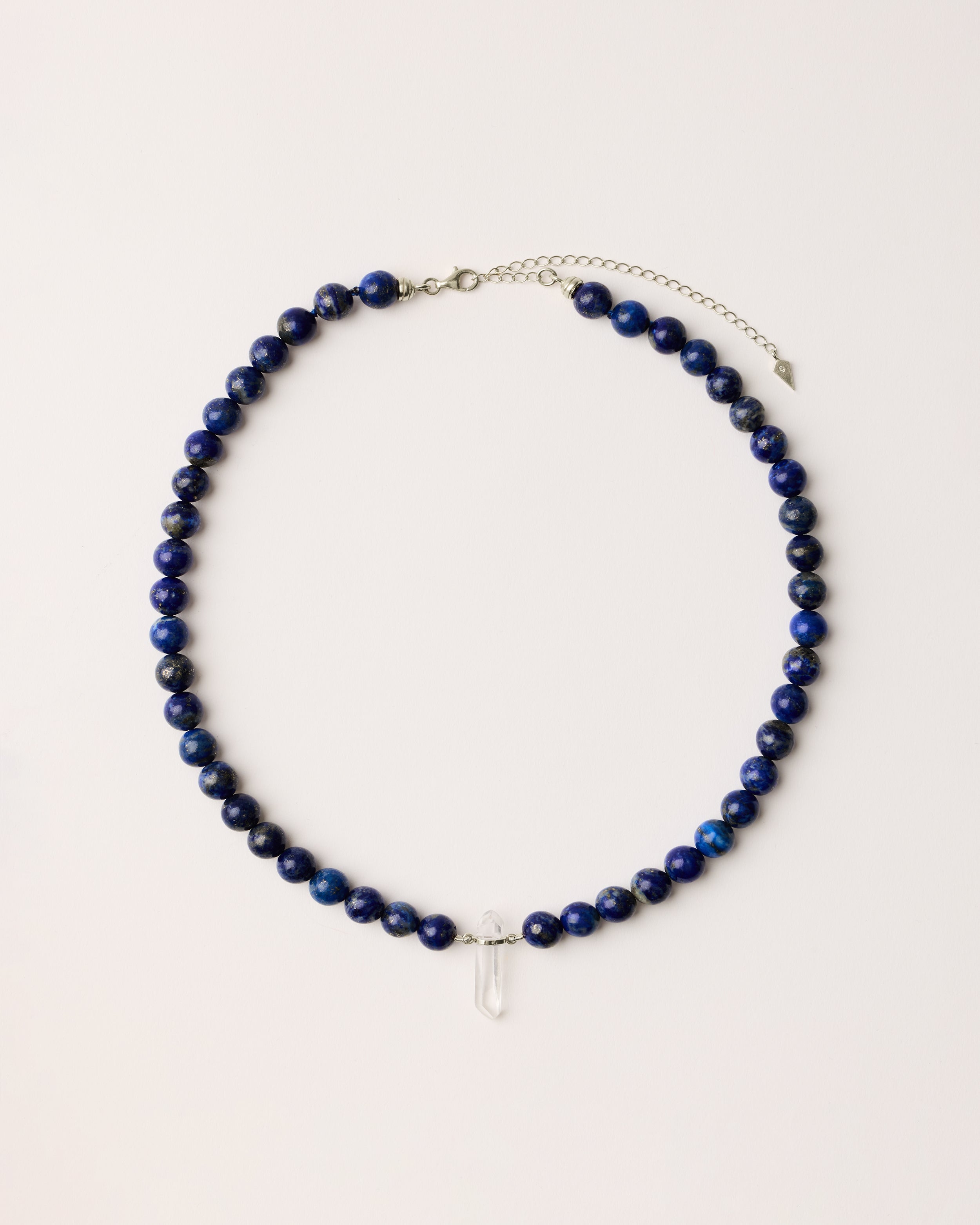 ENCARA NOCTA Lapis Lazuli necklace with raw polished quartz point pendant, silver 8 cm extension chain and clasp, arrowhead-shaped fantasy signature, and 8 mm faceted lazurite bead strand.