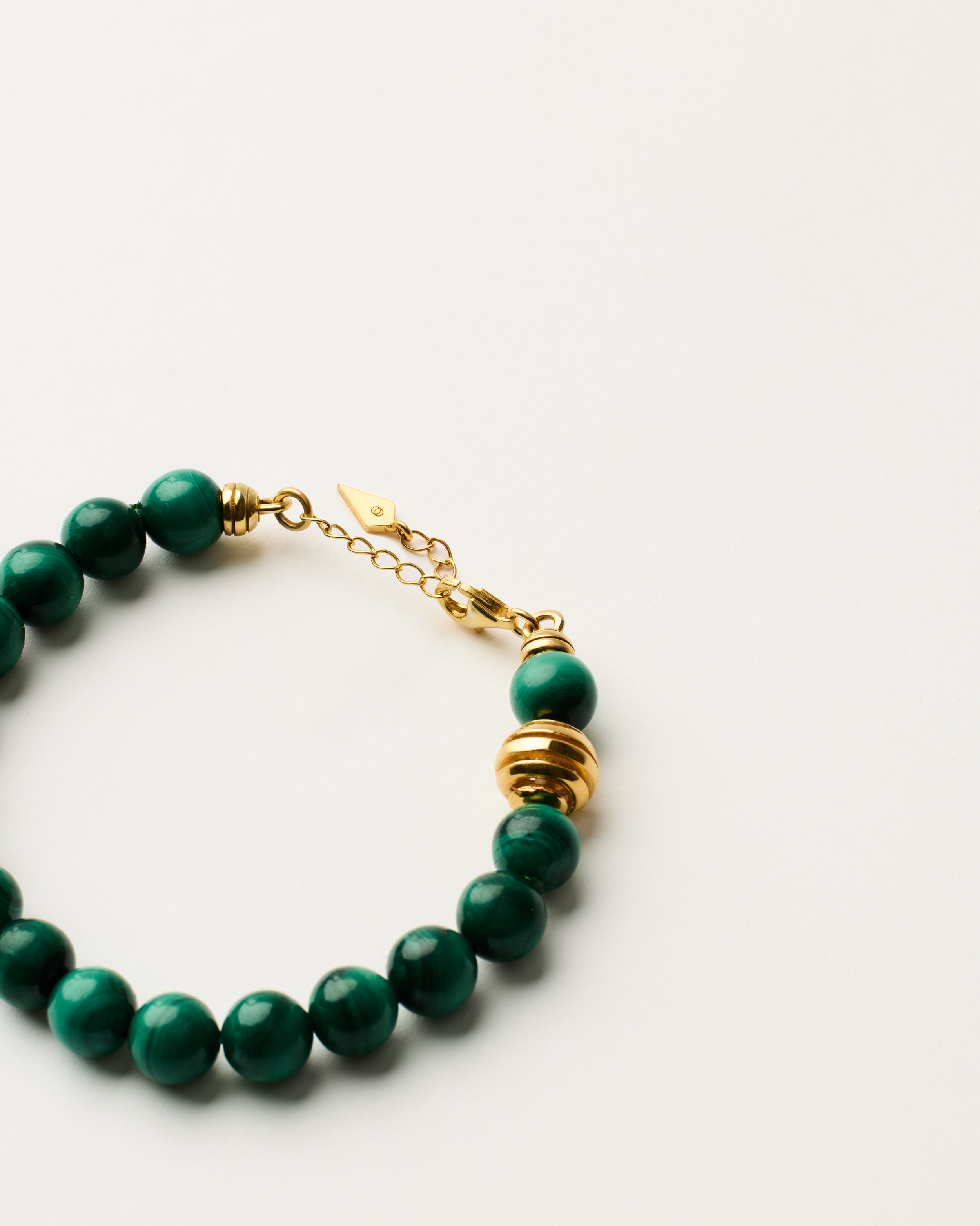 ETERNA VERDAN Malachite bracelet with polished gold-plated silver spiral bead, 4 cm extension chain and clasp, arrowhead-shaped fantasy signature, and 8 mm faceted malachite bead strand.