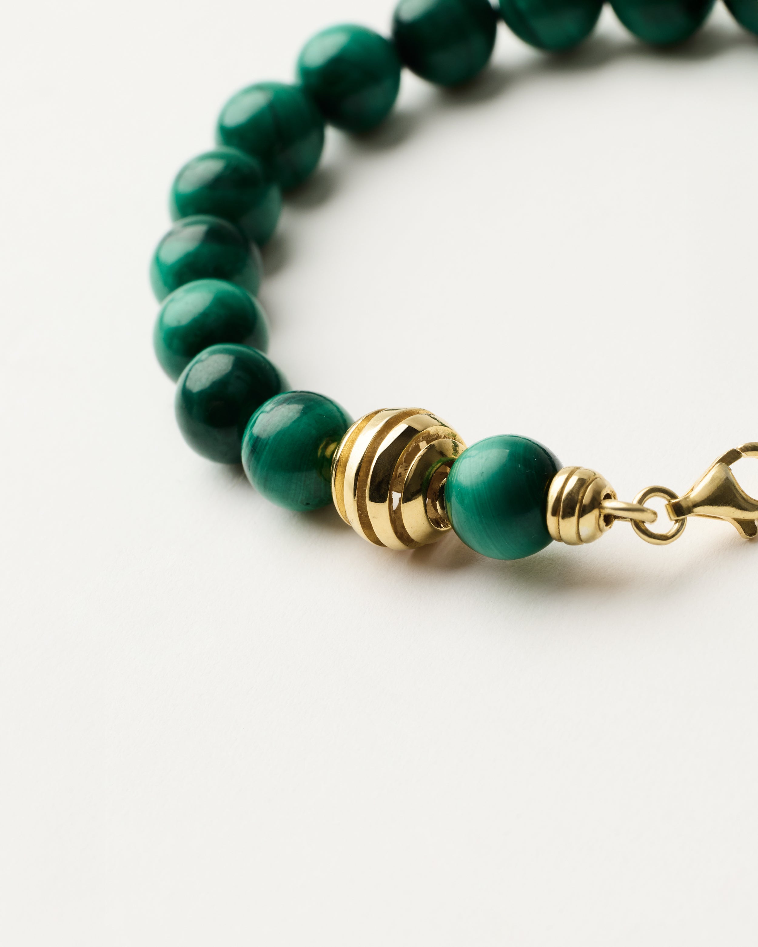ETERNA VERDAN Malachite bracelet with polished gold spiral bead, 4 cm extension chain and clasp, arrowhead-shaped fantasy signature, and 8 mm faceted malachite bead strand.