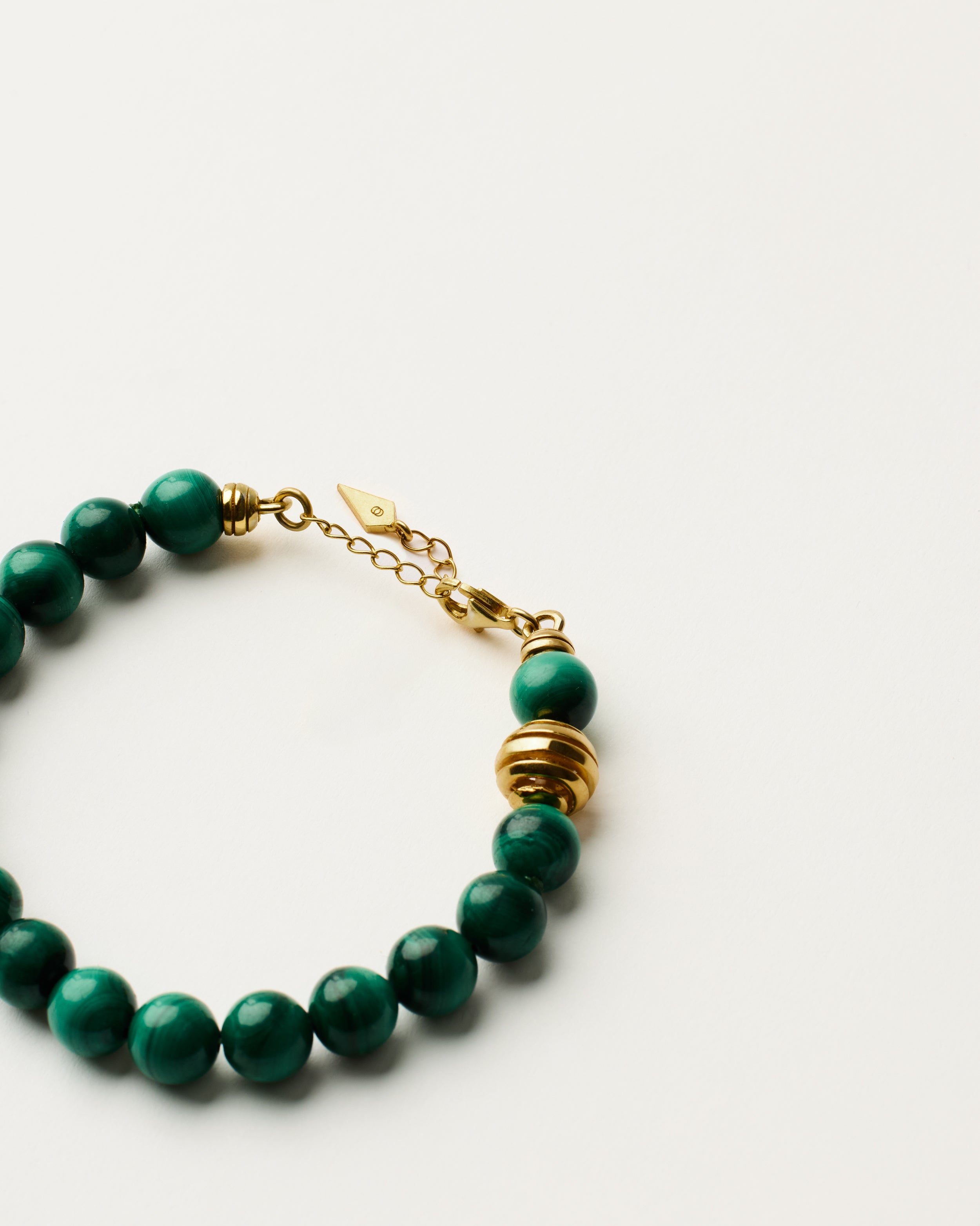 ETERNA VERDAN Malachite bracelet with polished gold spiral bead, 4 cm extension chain and clasp, arrowhead-shaped fantasy signature, and 8 mm faceted malachite bead strand.