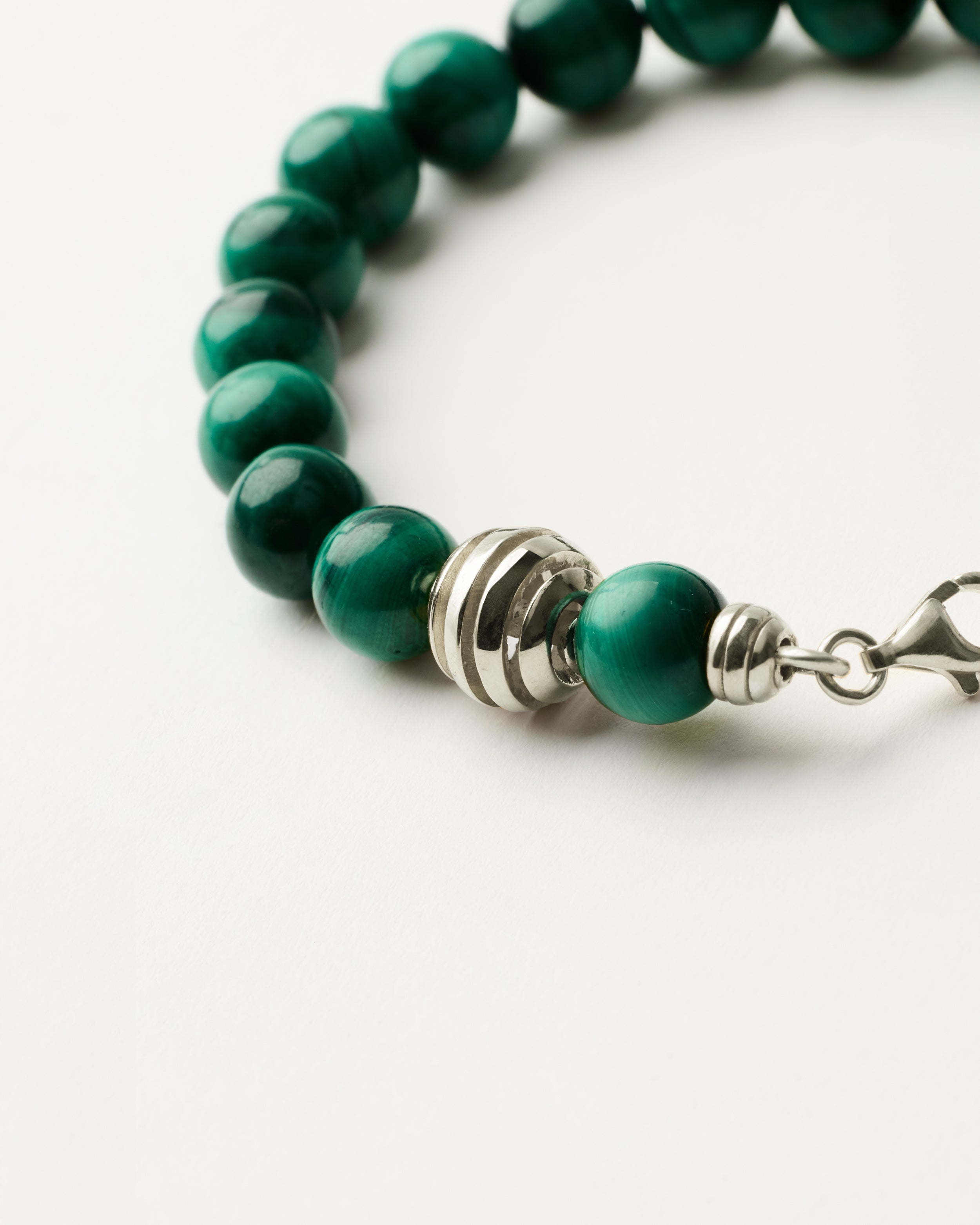 ETERNA VERDAN Malachite bracelet with polished silver spiral bead, 4 cm extension chain and clasp, arrowhead-shaped fantasy signature, and 8 mm faceted malachite bead strand.