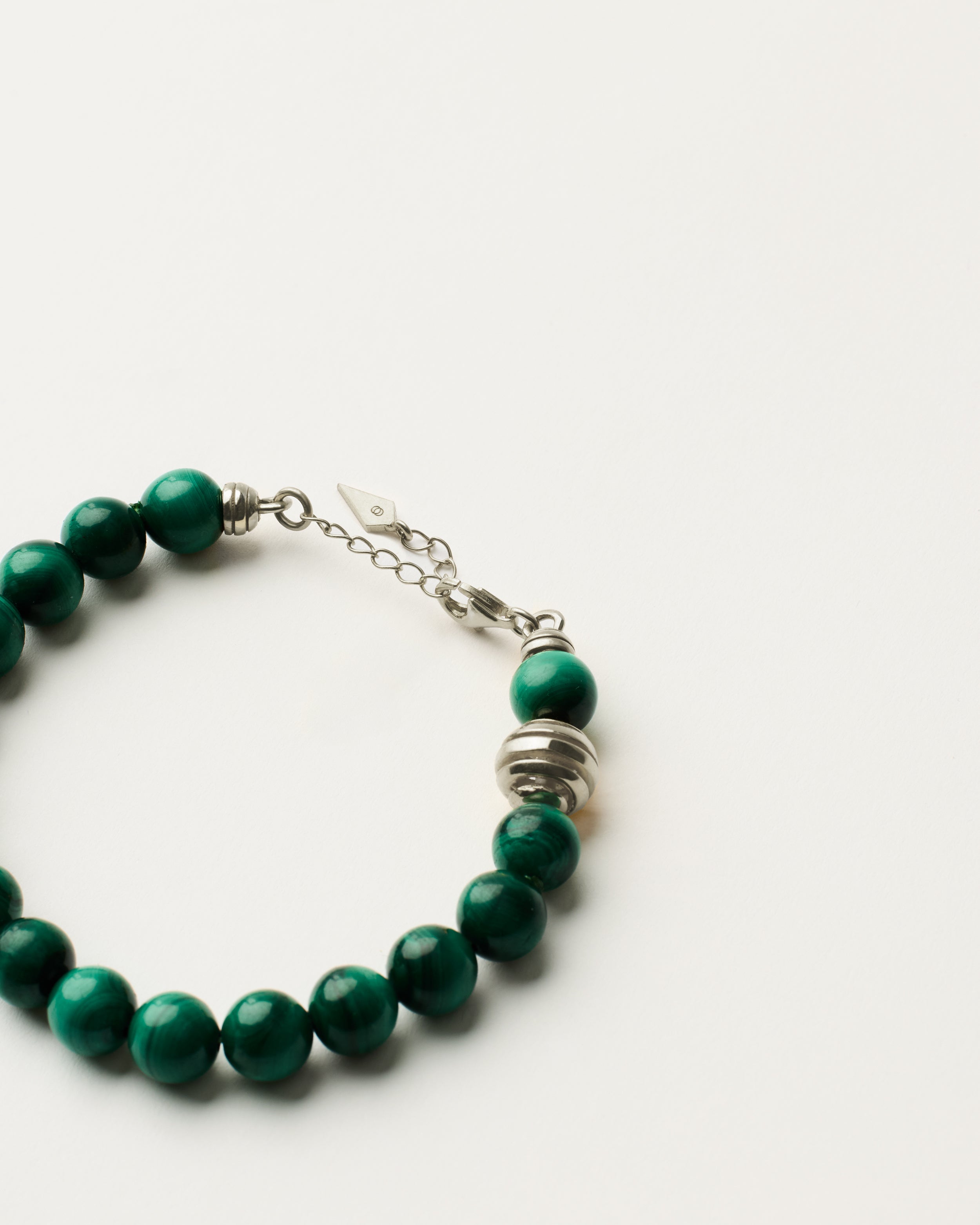 ETERNA VERDAN Malachite bracelet with polished silver spiral bead, 4 cm extension chain and clasp, arrowhead-shaped fantasy signature, and 8 mm faceted malachite bead strand.