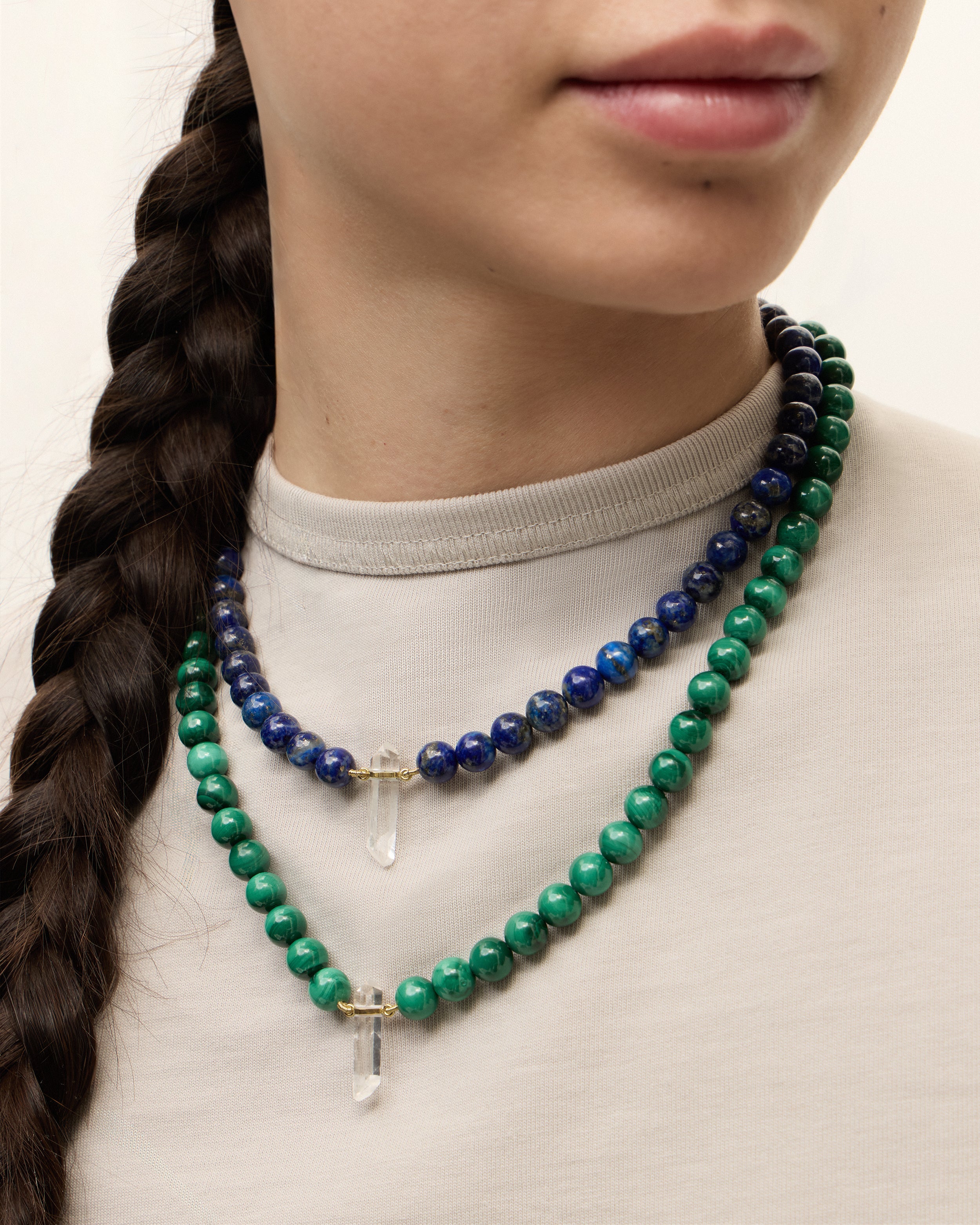 ENCARA NOCTA Lapis Lazuli / ENCARA VERDAN Malachite necklace with raw polished quartz point pendant, gold 8 cm extension chain and clasp, arrowhead-shaped fantasy signature, and 8 mm faceted lazurite / malachite bead strand.
