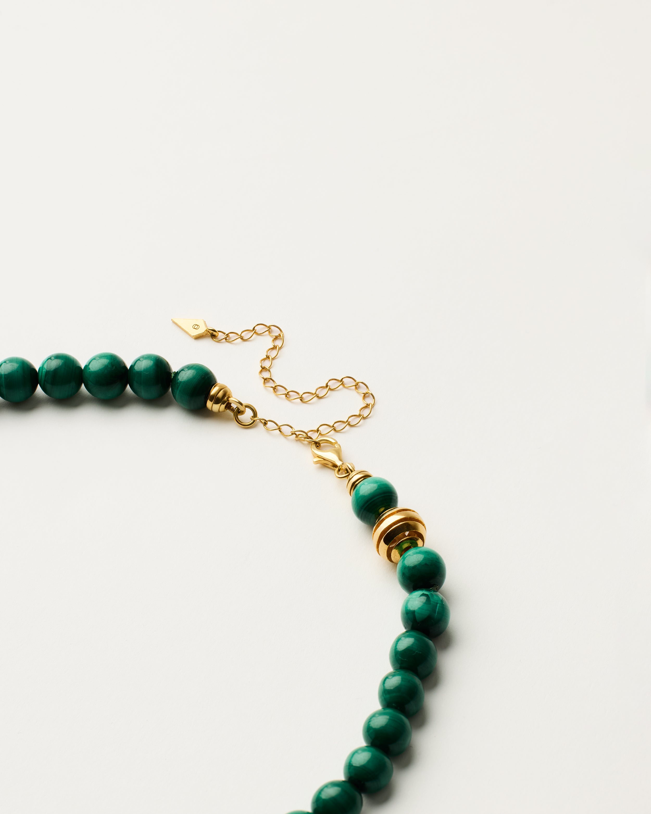 ETERNA VERDAN Malachite necklace with polished gold-plated silver spiral bead, 8 cm extension chain and clasp, arrowhead-shaped fantasy signature, and 8 mm faceted malachite bead strand.