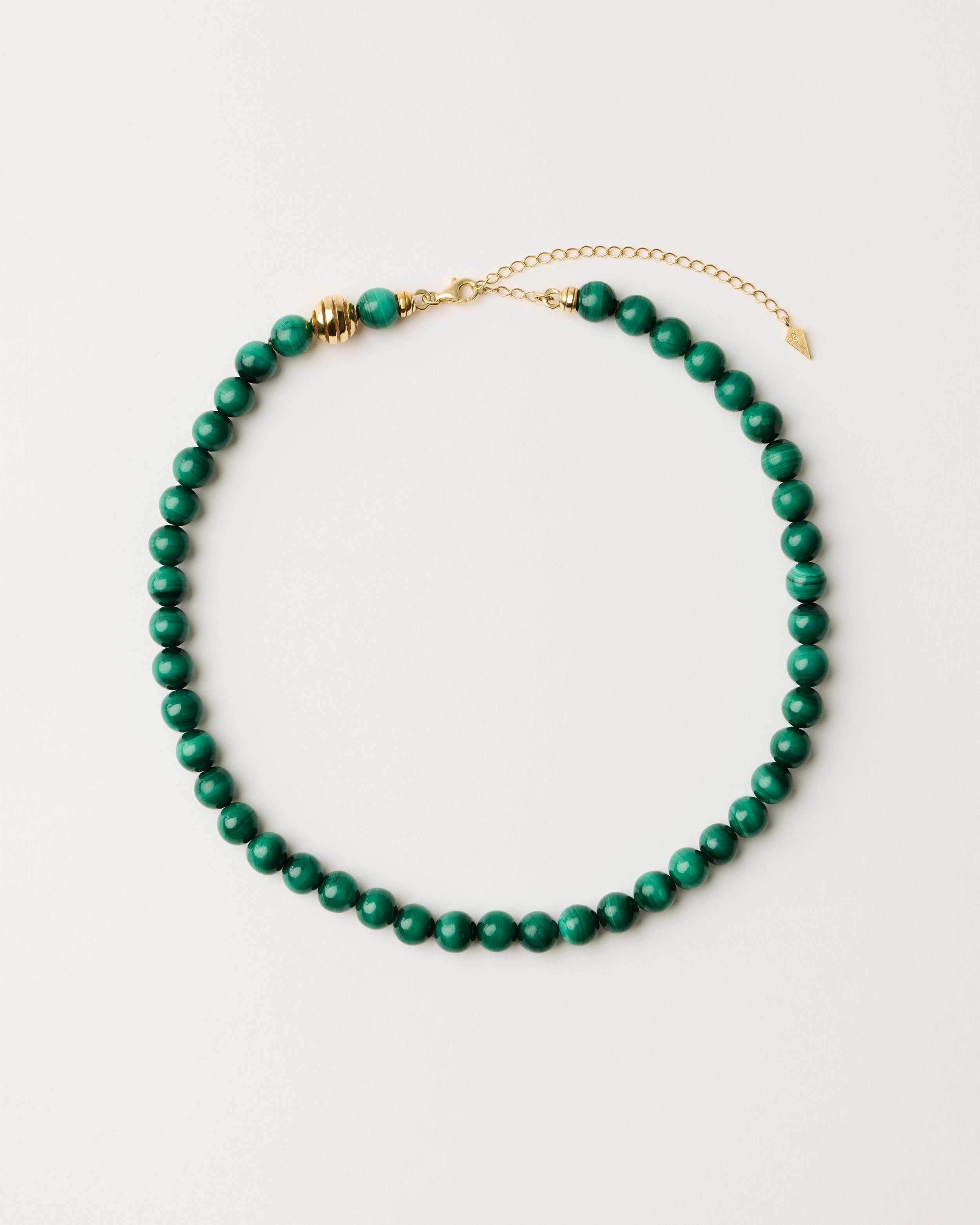 ETERNA VERDAN Malachite necklace with polished gold spiral bead, 8 cm extension chain and clasp, arrowhead-shaped fantasy signature, and 8 mm faceted malachite bead strand.