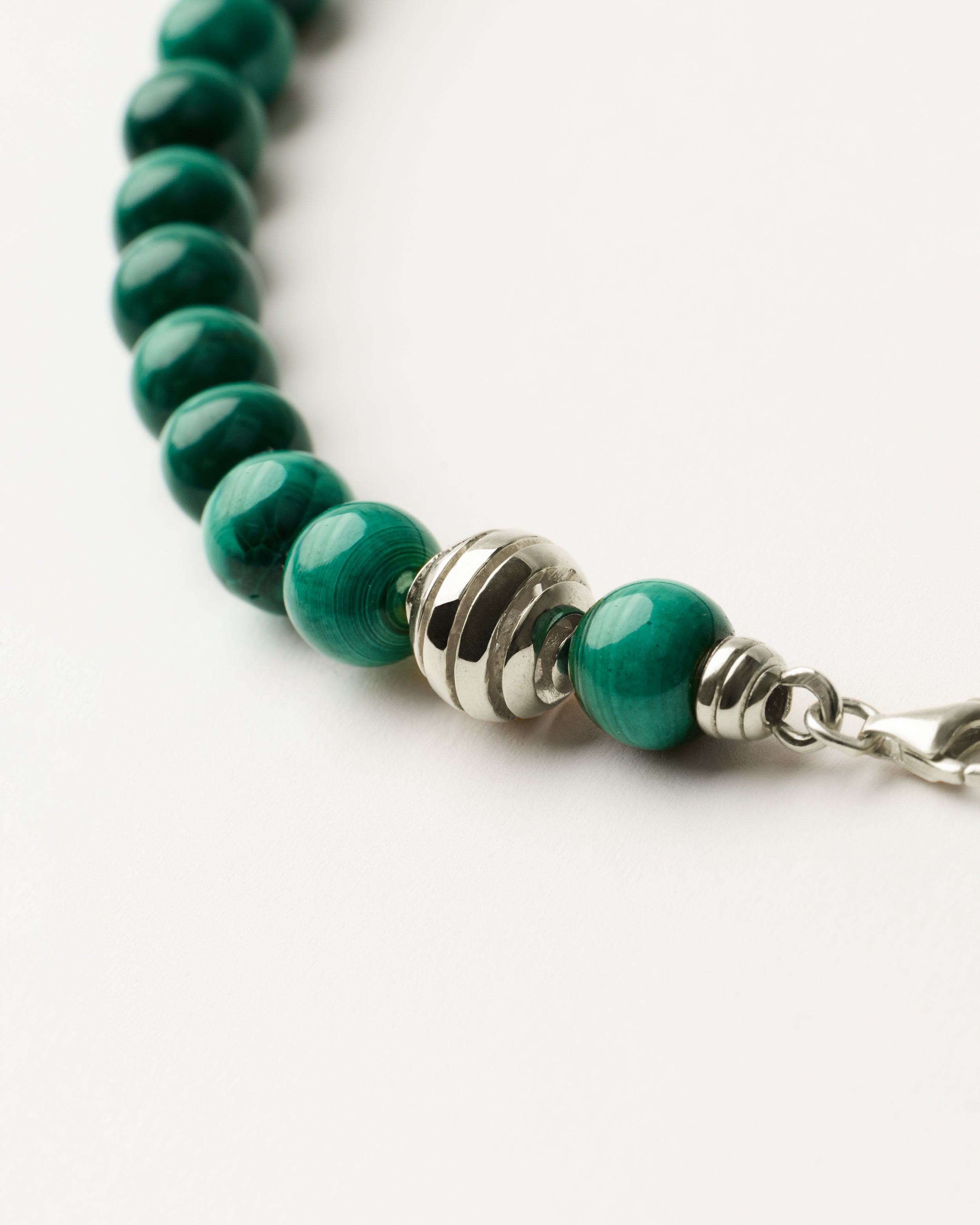 ETERNA VERDAN Malachite necklace with polished silver spiral bead, 8 cm extension chain and clasp, arrowhead-shaped fantasy signature, and 8 mm faceted malachite bead strand.