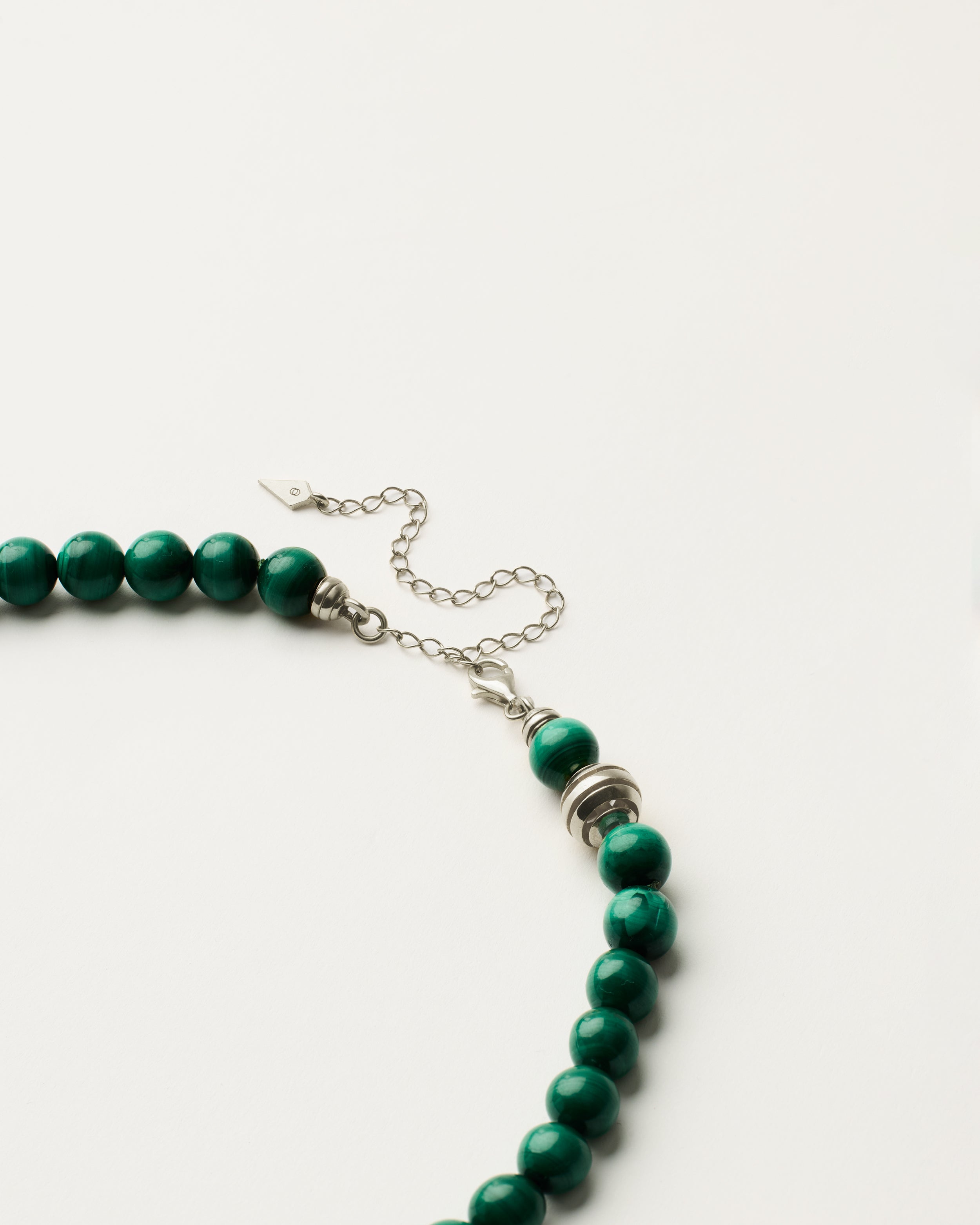 ETERNA VERDAN Malachite necklace with polished silver spiral bead, 8 cm extension chain and clasp, arrowhead-shaped fantasy signature, and 8 mm faceted malachite bead strand.