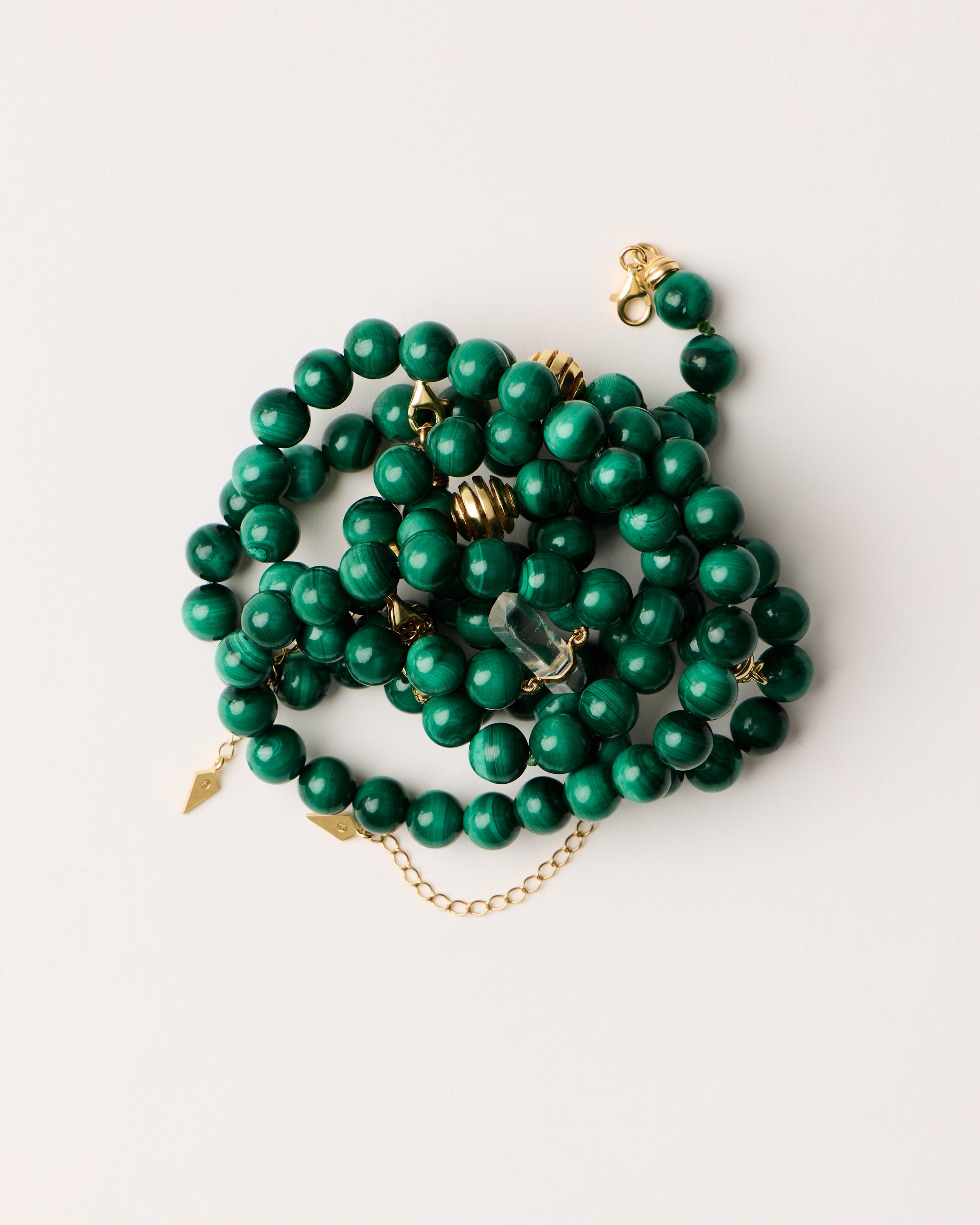ENCARA / ETERNA VERDAN Malachite necklaces and bracelet with polished gold spiral bead, extension chain and clasp, arrowhead-shaped fantasy signature, and 8 mm faceted malachite bead strand and raw polished quartz point pendant.