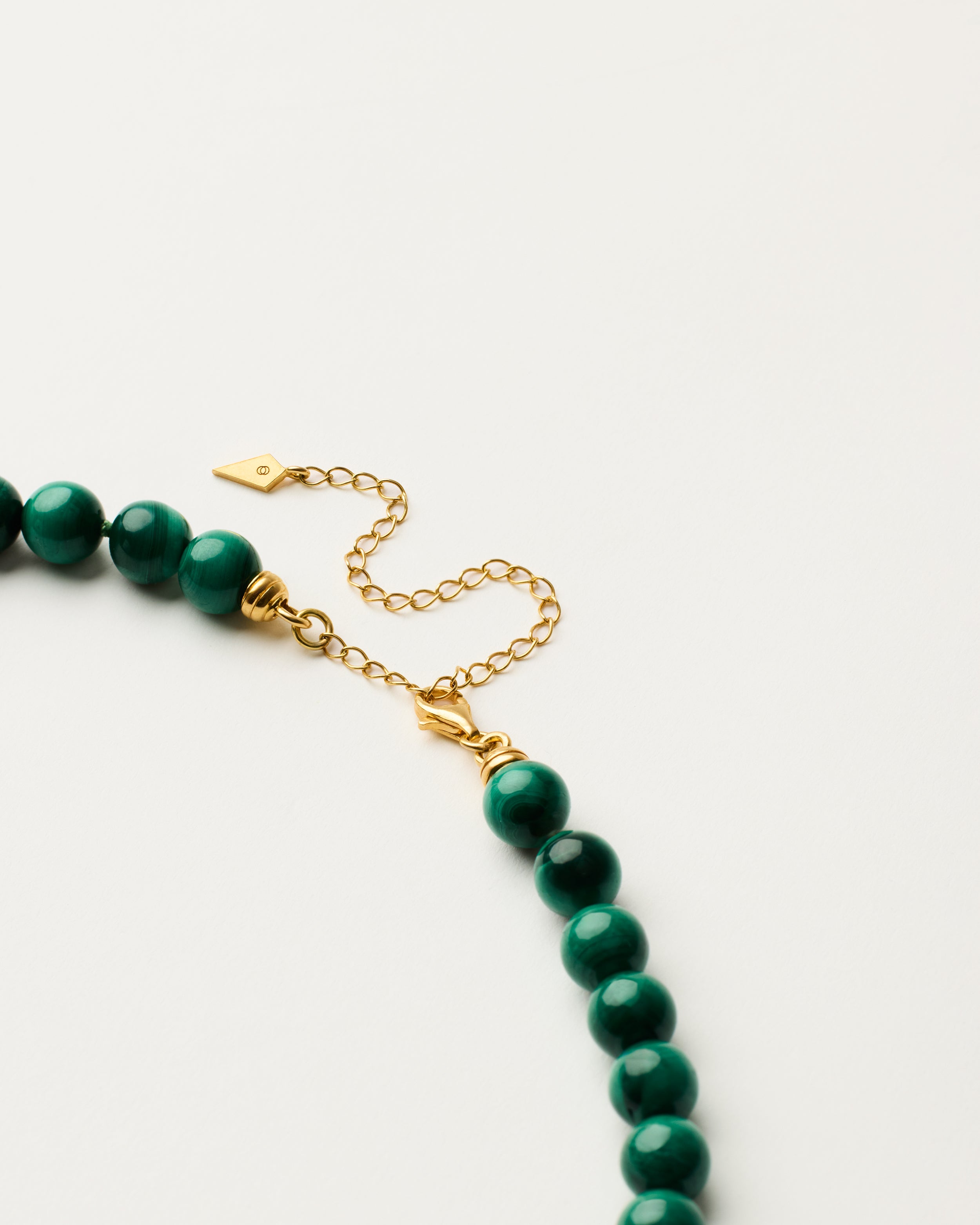 ENCARA VERDAN Malachite necklace with raw polished quartz point pendant, gold-plated silver 8 cm extension chain and clasp, arrowhead-shaped fantasy signature, and 8 mm faceted malachite bead strand.