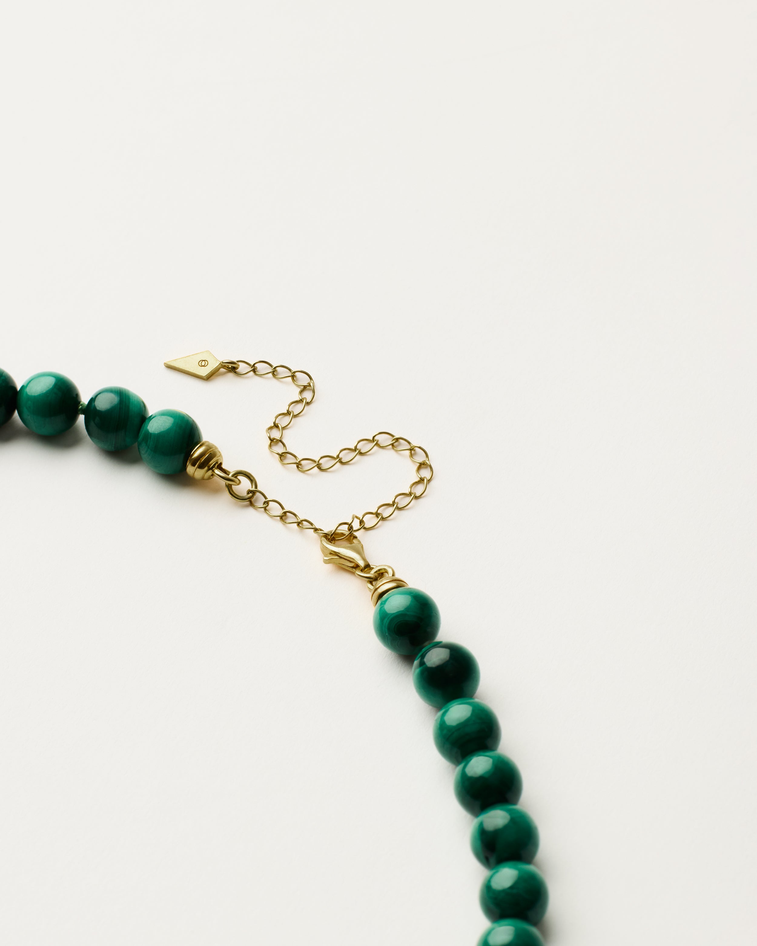 ENCARA VERDAN Malachite necklace with raw polished quartz point pendant, gold 8 cm extension chain and clasp, arrowhead-shaped fantasy signature, and 8 mm faceted malachite bead strand.