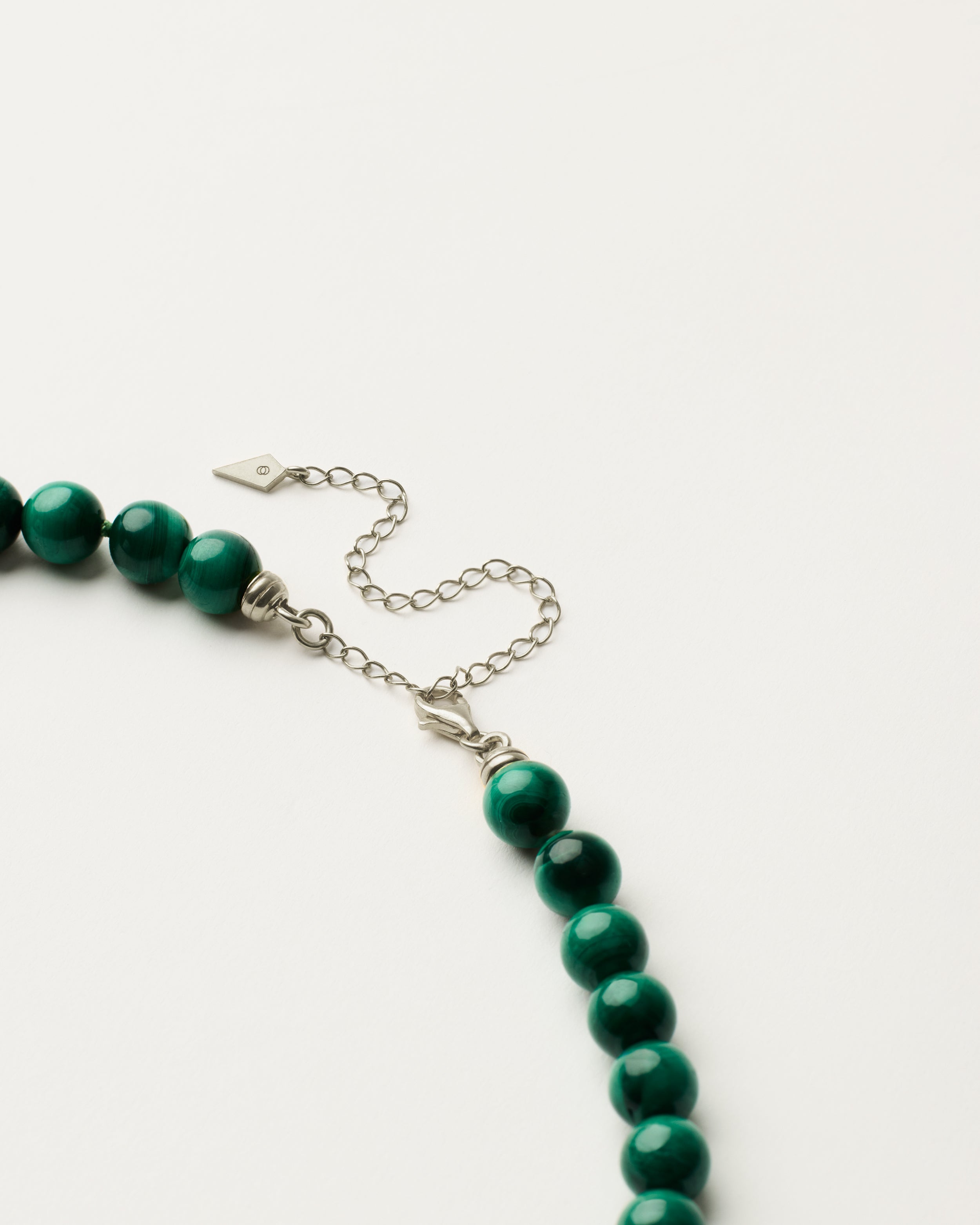 ENCARA VERDAN Malachite necklace with raw polished quartz point pendant, silver 8 cm extension chain and clasp, arrowhead-shaped fantasy signature, and 8 mm faceted malachite bead strand.