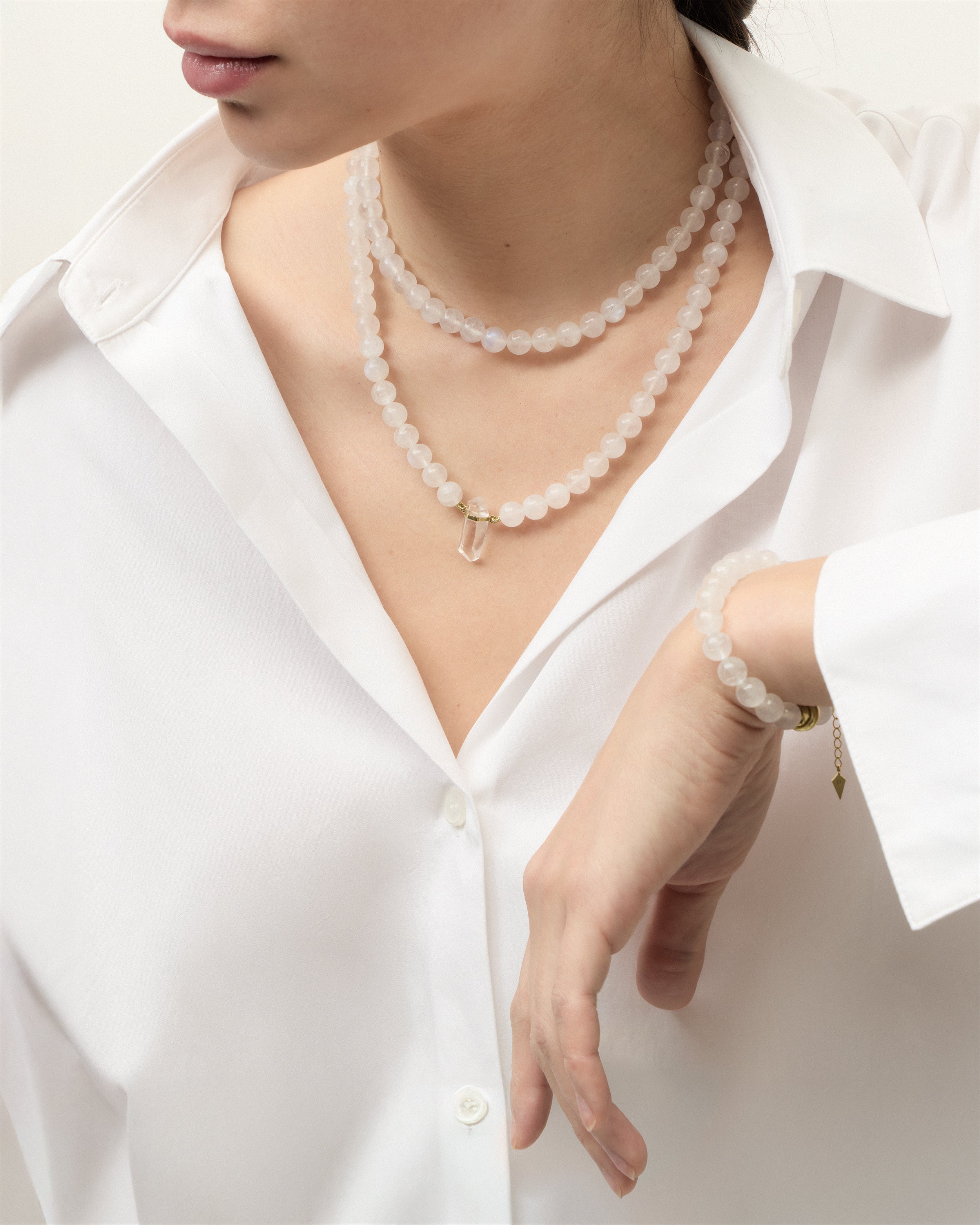 ENCARA / ETERNA LUNOR Moonstone necklaces and bracelet with polished gold spiral bead, extension chain and clasp, arrowhead-shaped fantasy signature, and 8 mm faceted moonstone bead strand and raw polished quartz point pendant.